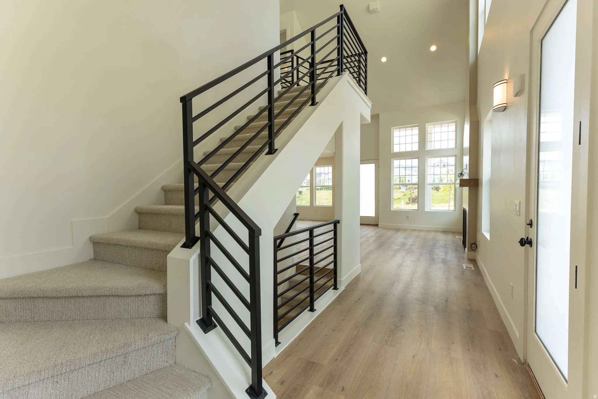 Contemporary staircase featuring black metal railings and light-colored carpeted treads