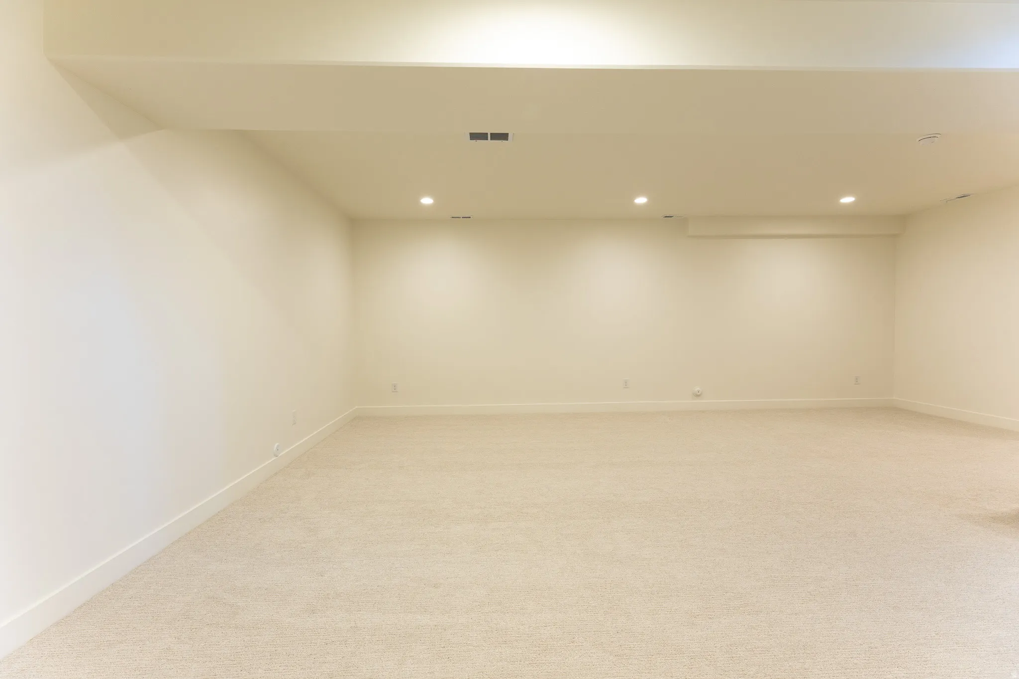 Spacious room featuring neutral carpet flooring, recessed lighting, and white baseboards