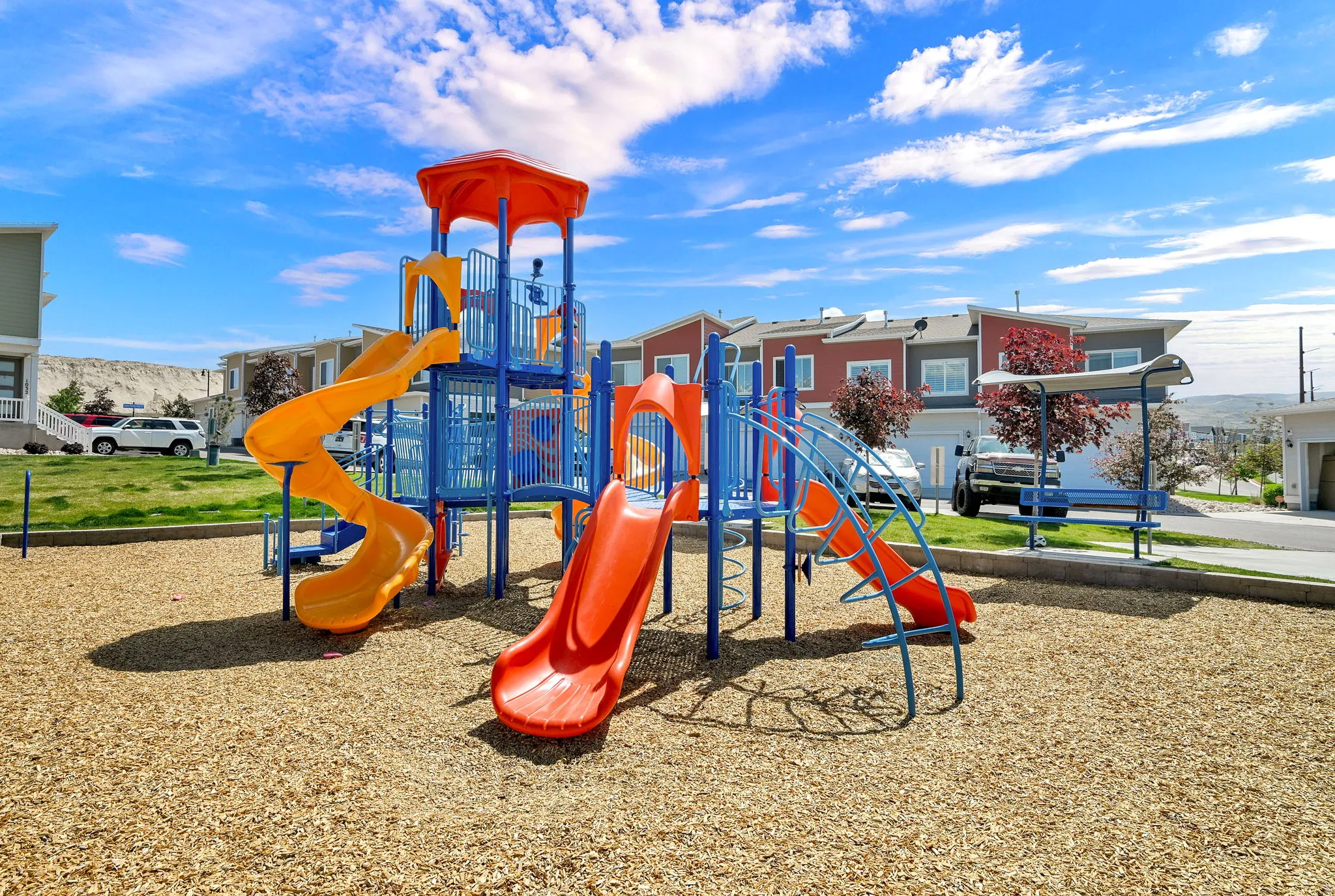 Community playground featuring multiple slides and climbing structures over wood chip surfacing
