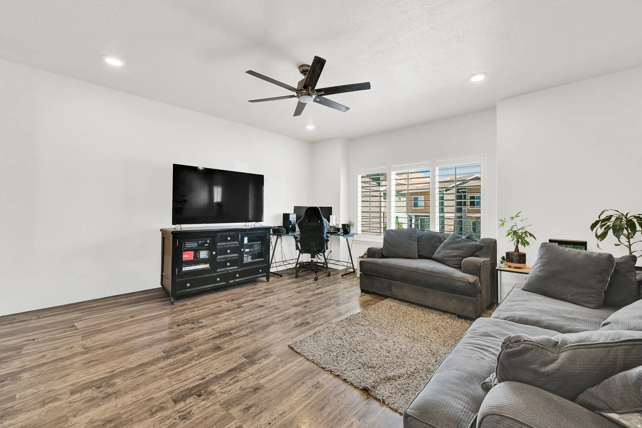 Bright living area featuring wood-finish flooring, white walls, and recessed lighting