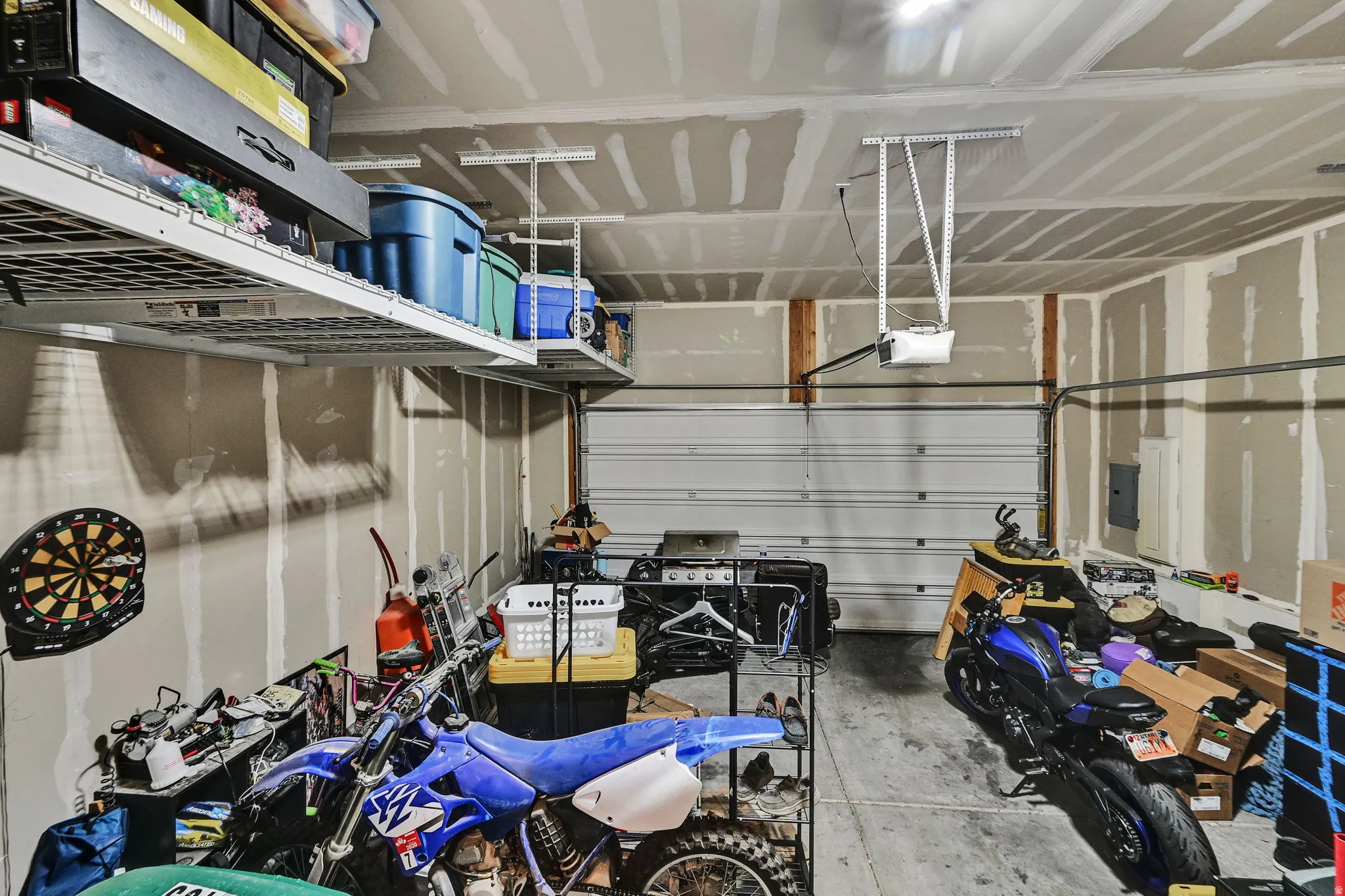 Garage space featuring an overhead door, exposed wall studs, and ceiling-mounted storage racks