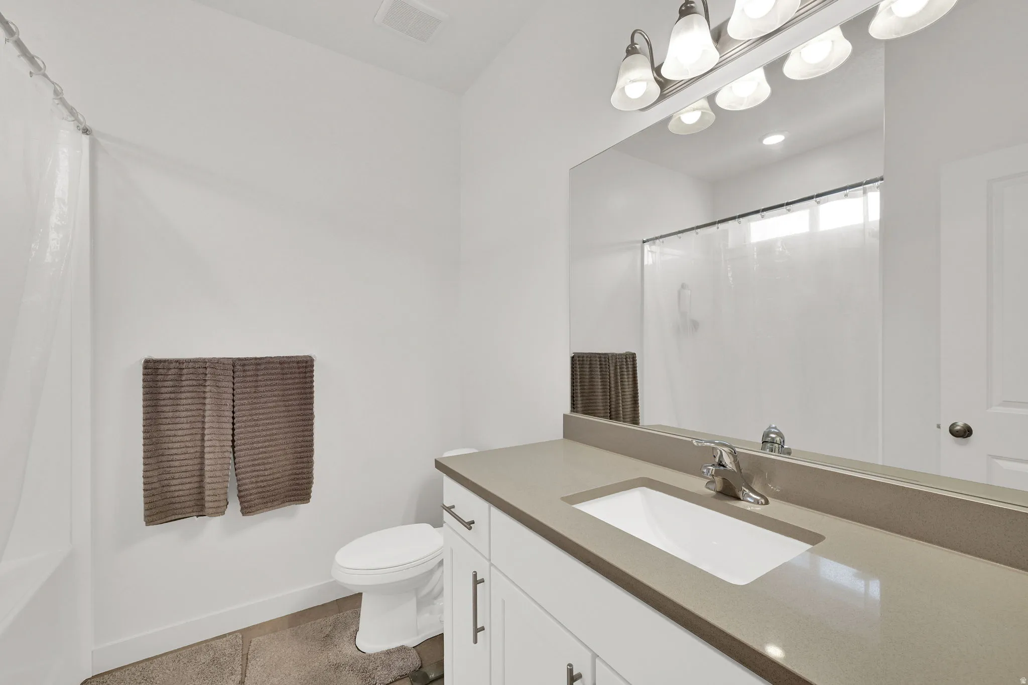 Bathroom featuring a white vanity with brushed nickel hardware, an integrated sink, and a light-toned countertop