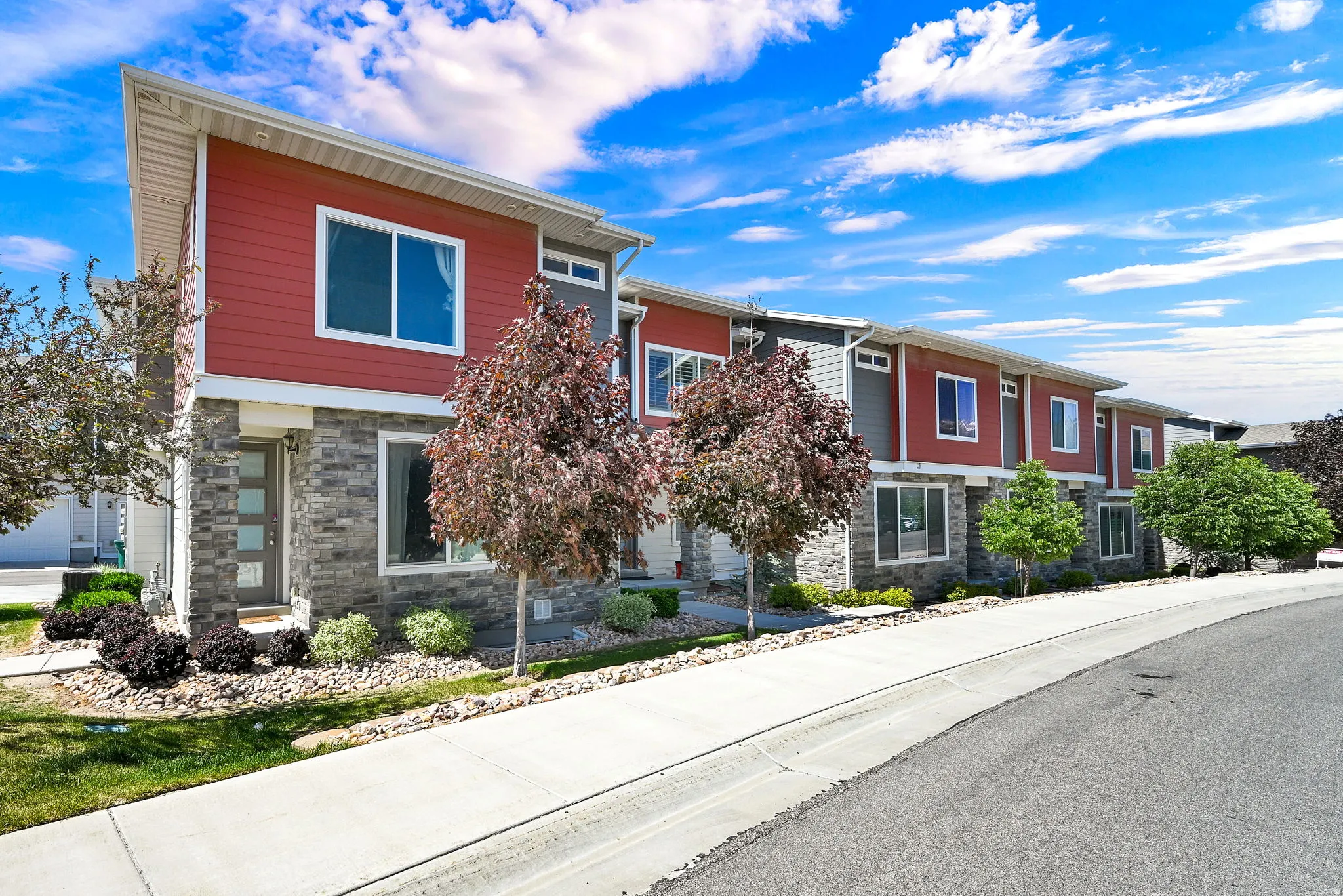 Contemporary townhome exterior featuring red siding and stone veneer accents