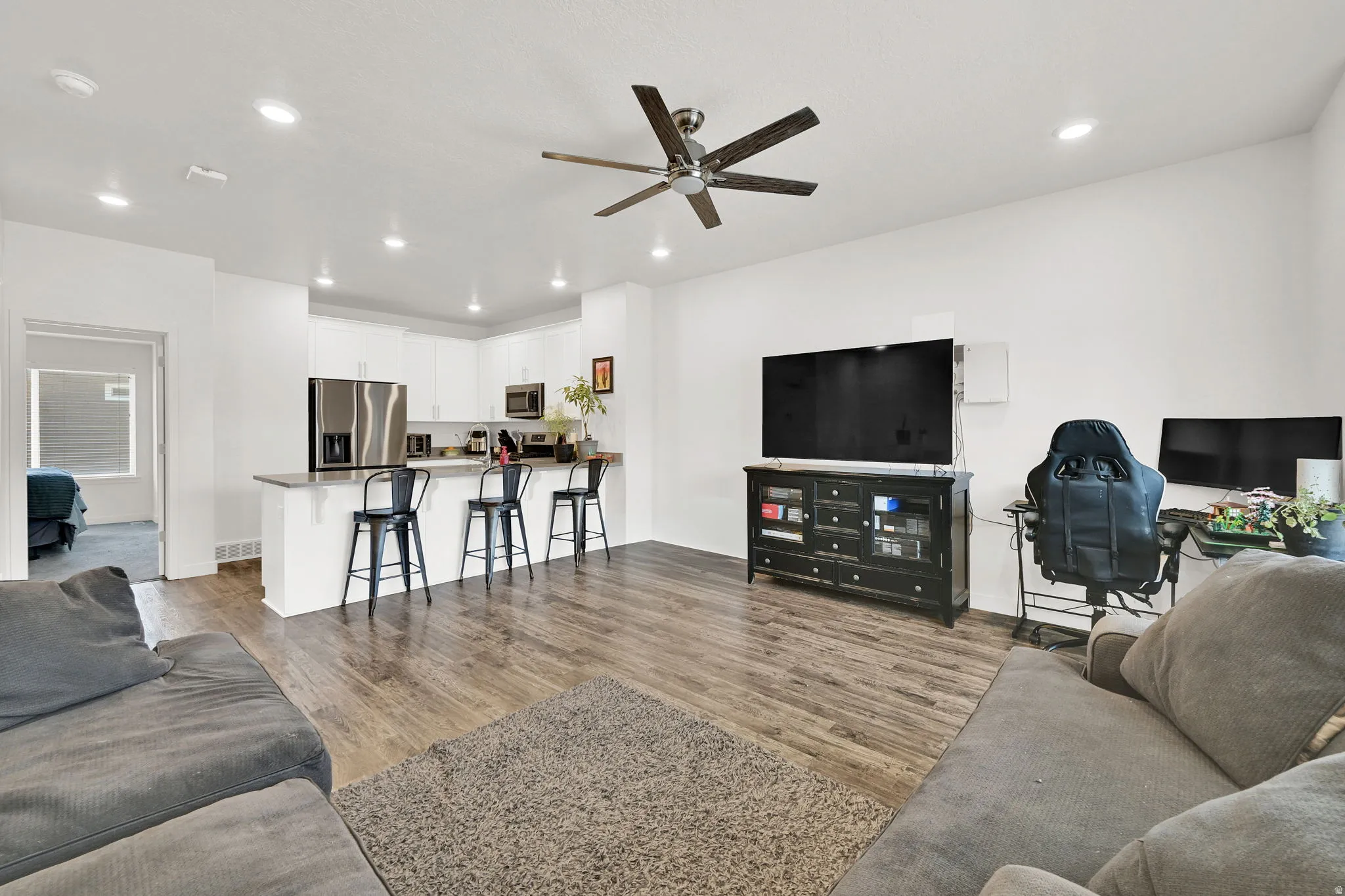 Open-concept living space featuring wood-finish flooring, recessed lighting, and a ceiling fan