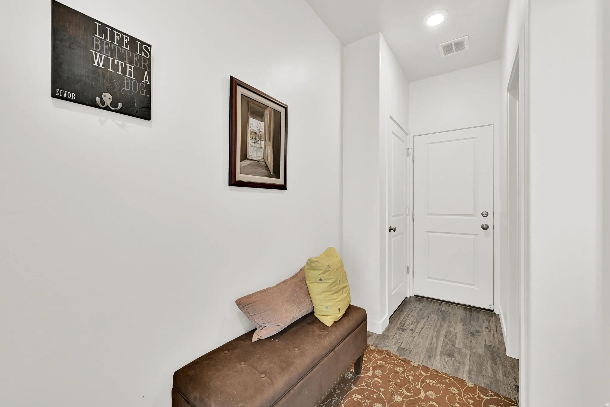Bright hallway featuring white walls, recessed lighting, and wood-finish flooring