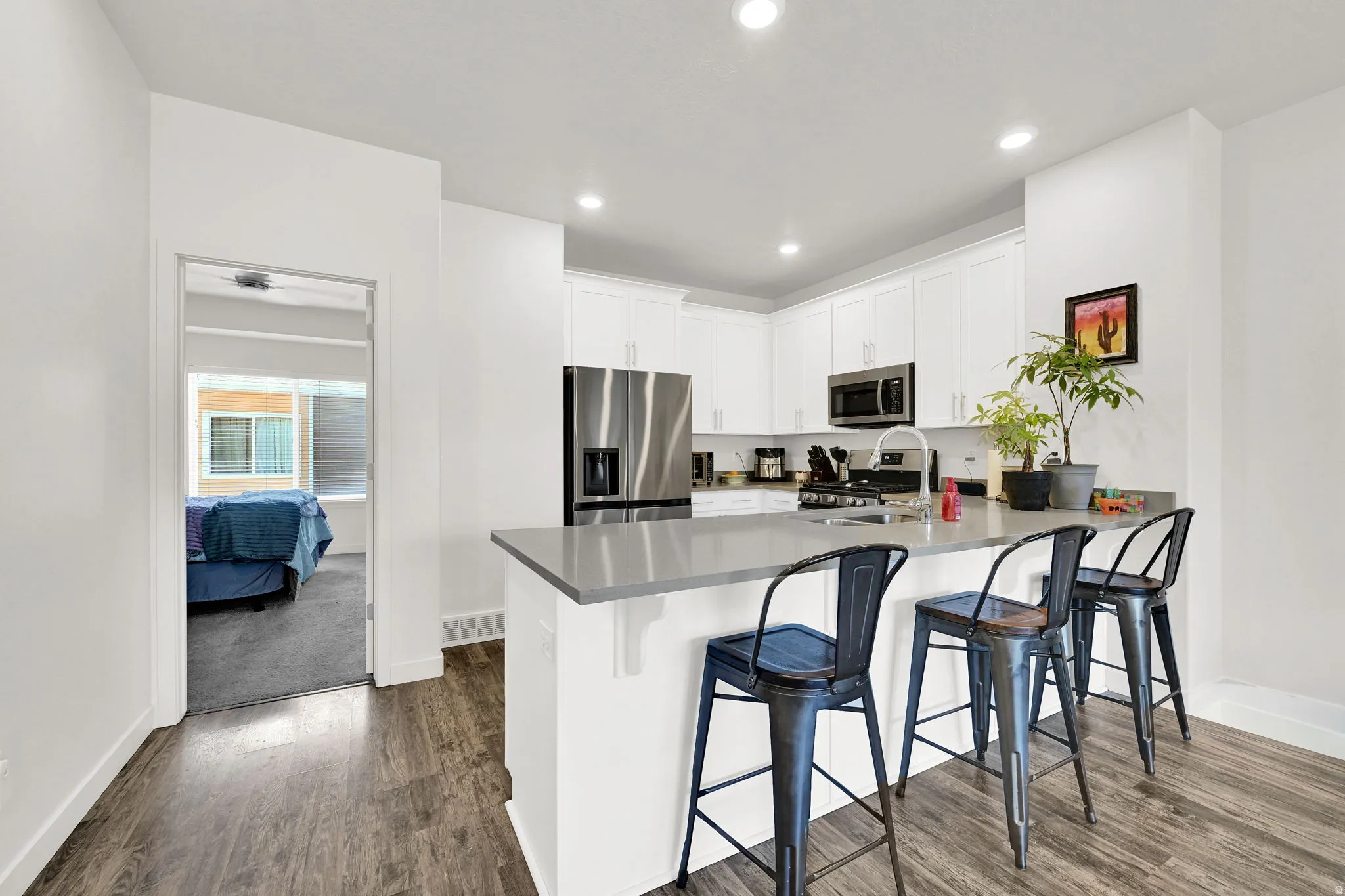 Modern kitchen featuring white cabinetry, stainless steel appliances, and a grey countertop with a breakfast bar