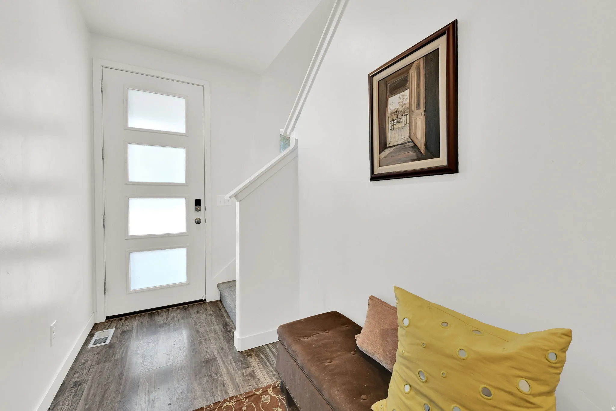 Entryway featuring a modern door with four frosted glass panels, wood-finish flooring, and a staircase with a white railing