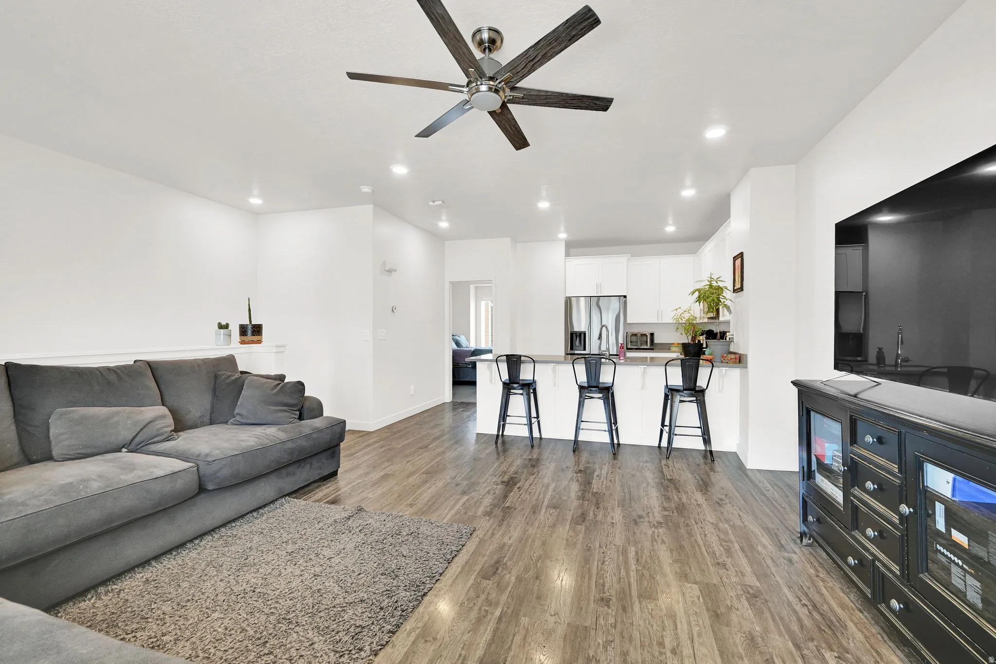 Open-concept living space featuring wood-finish flooring, recessed lighting, and a ceiling fan