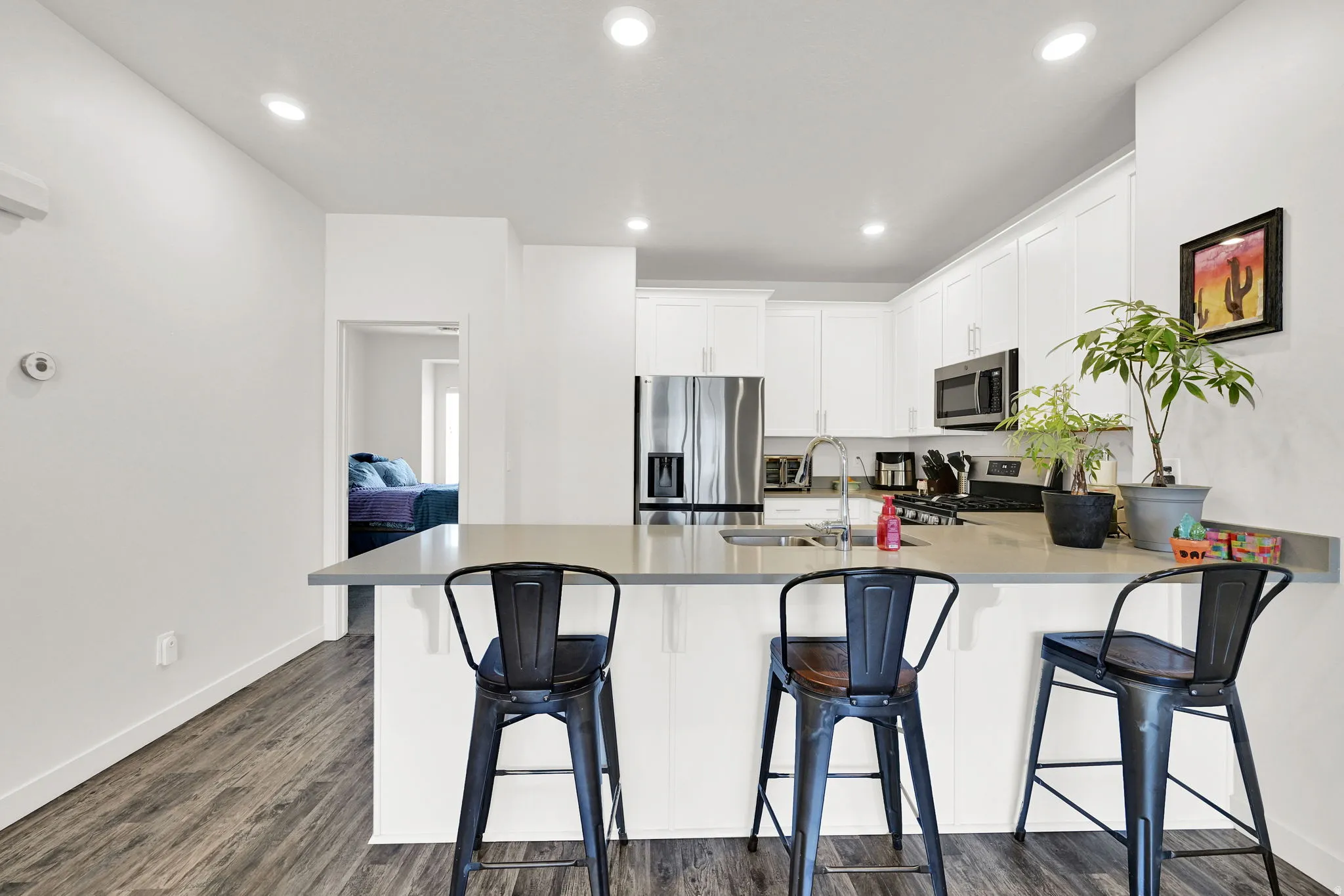 Kitchen featuring white shaker cabinetry, stainless steel appliances, and a light-toned countertop with an integrated sink