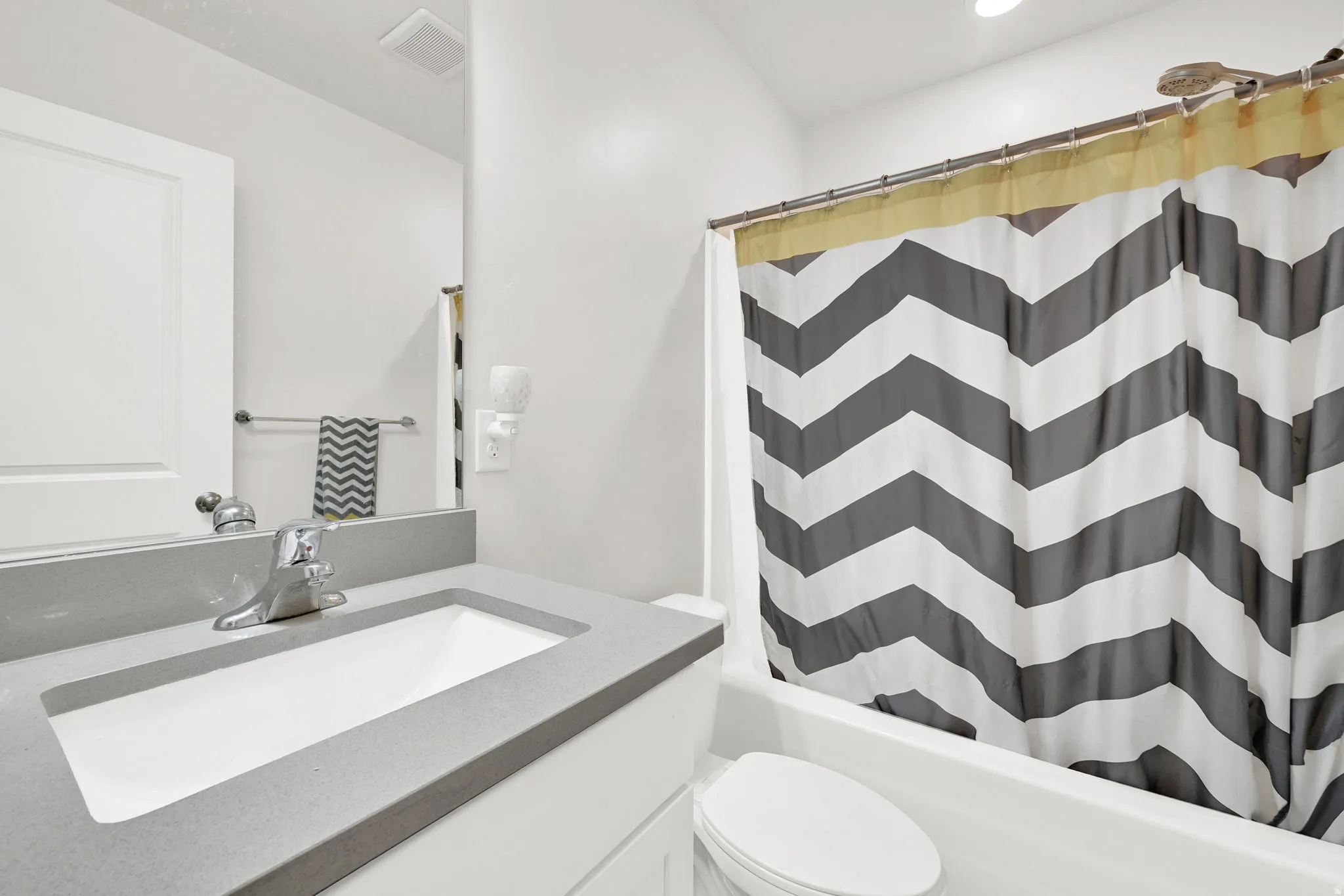 Bathroom featuring a white integrated sink with a gray countertop, a chrome faucet, and a white vanity