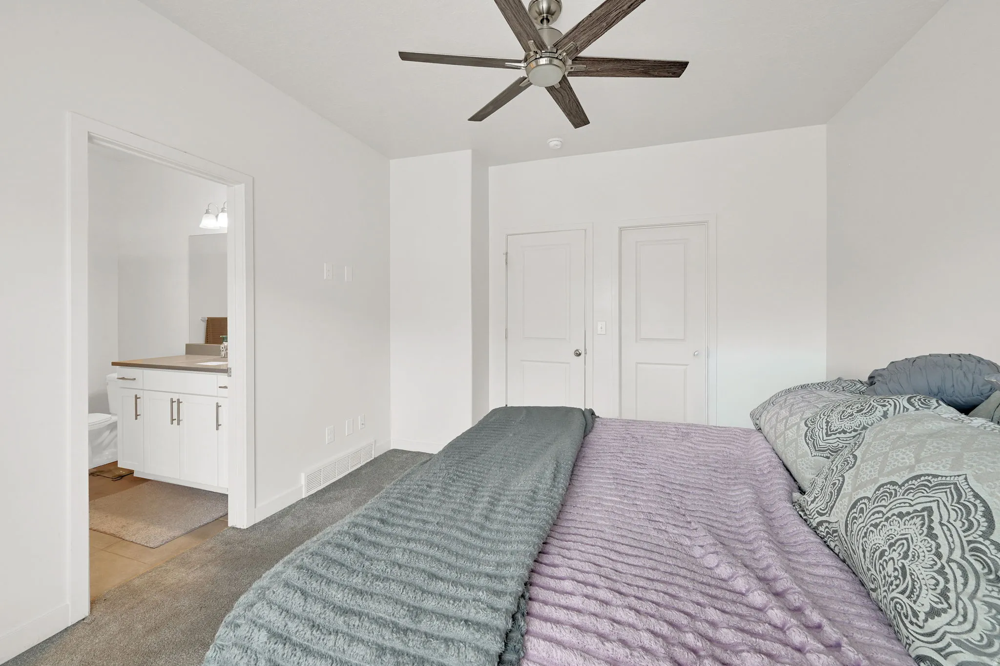 Bedroom featuring a ceiling fan with wood-look blades and brushed nickel accents, neutral carpet flooring, and white painted walls
