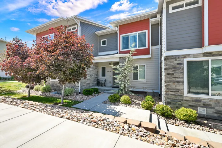 Modern townhome exterior featuring stone accents, horizontal siding, and a contrasting red facade