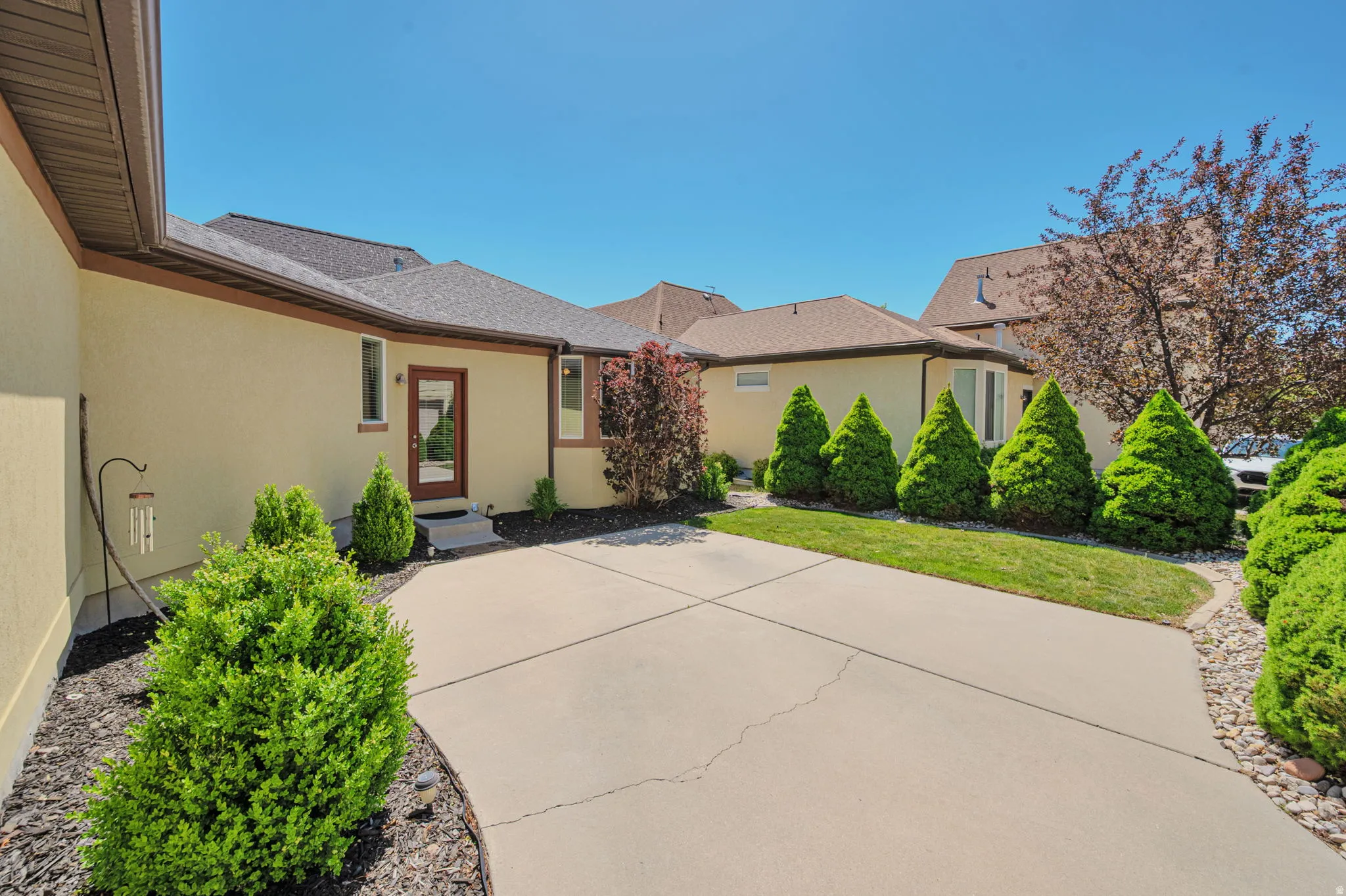 Stucco exterior with brown trim and a dark shingle roof
