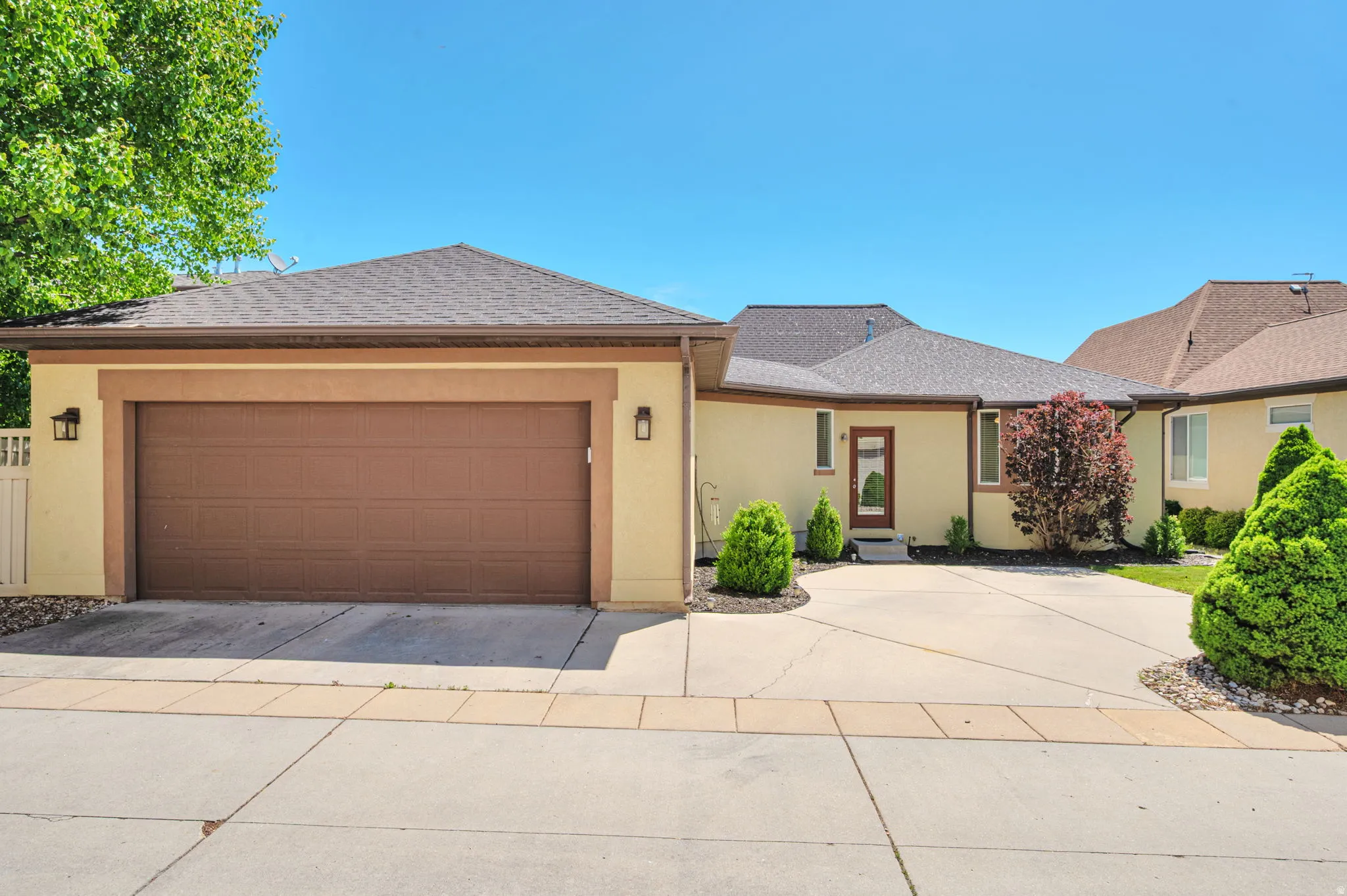 Stucco exterior with an attached two-car garage featuring a brown panel door