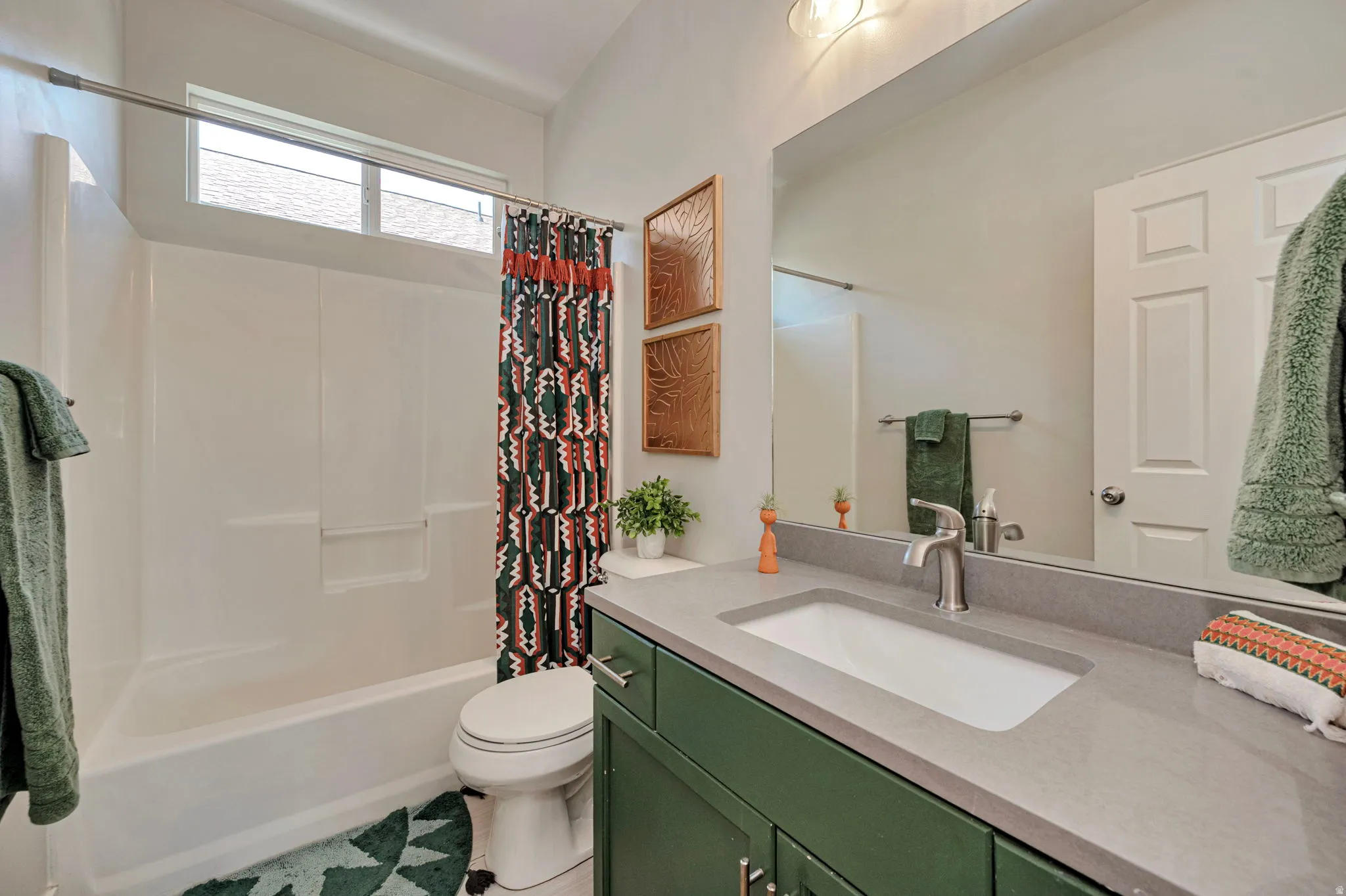 Bathroom featuring a single vanity with a rectangular sink, a gray countertop, and green cabinetry