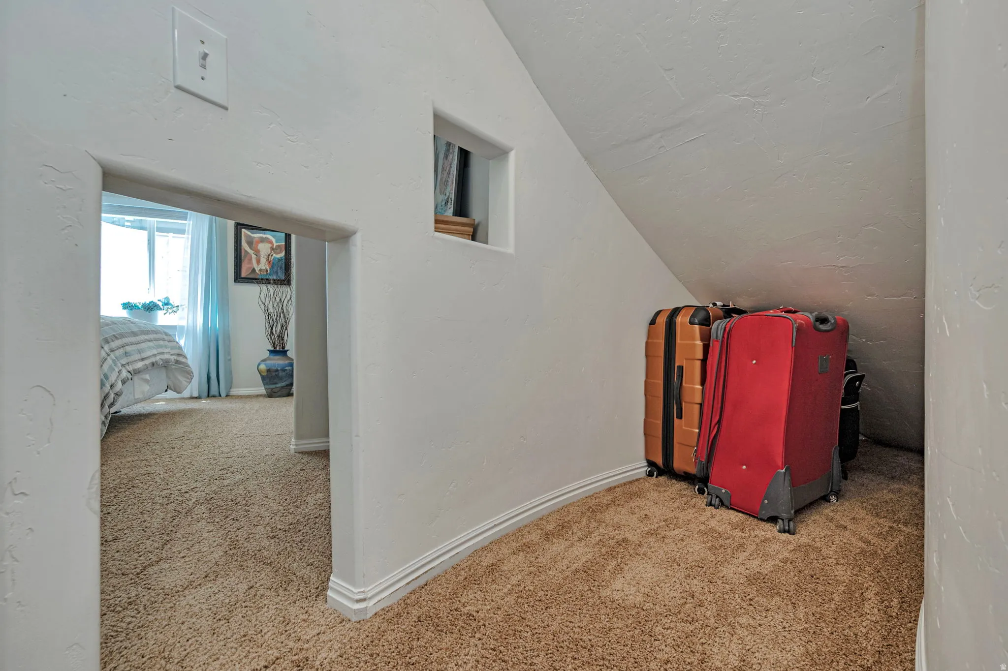 Carpeted attic space featuring a built-in niche and sloped ceiling