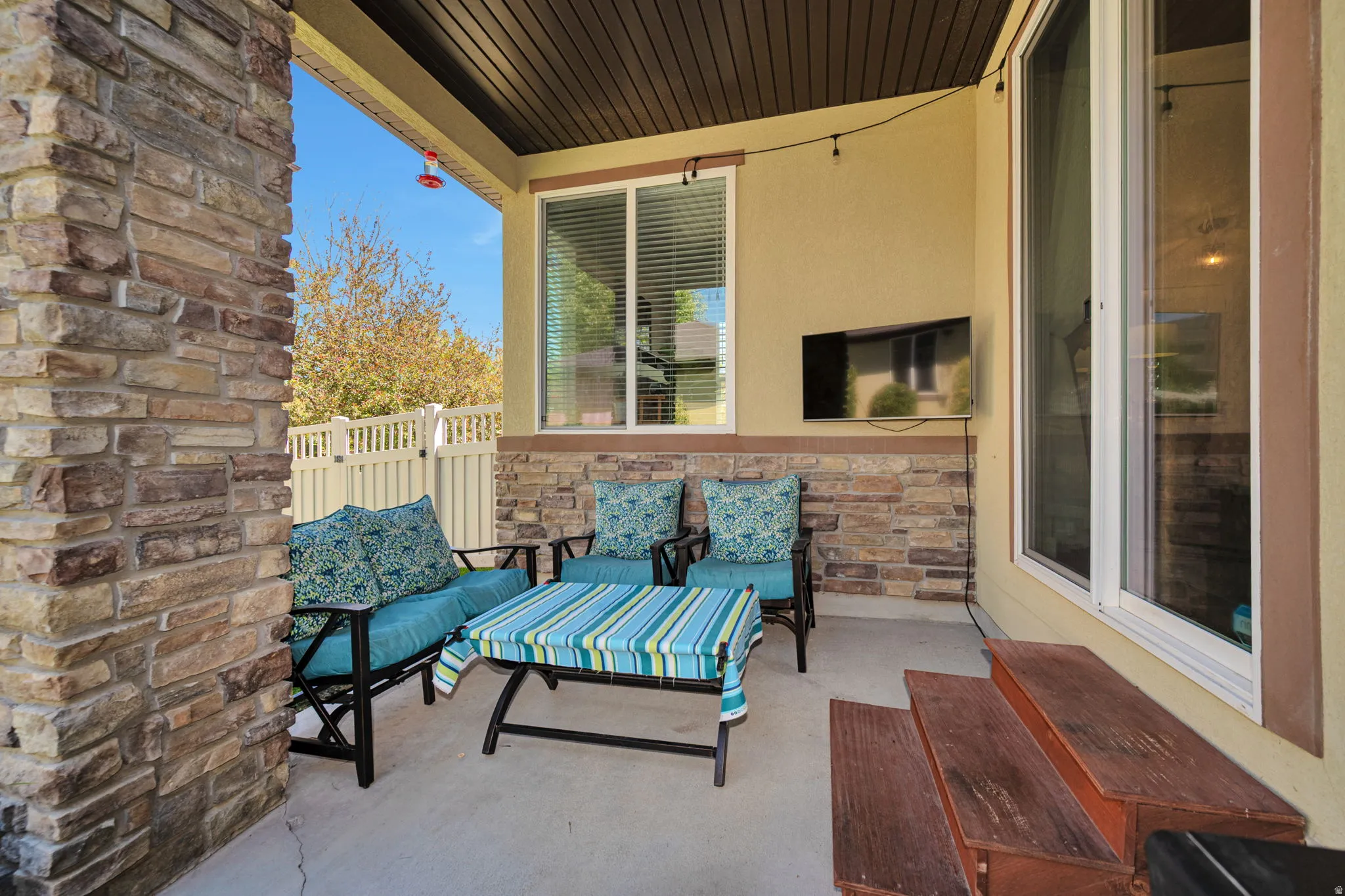 Covered patio featuring a stone veneer accent wall, solid ceiling, and concrete flooring