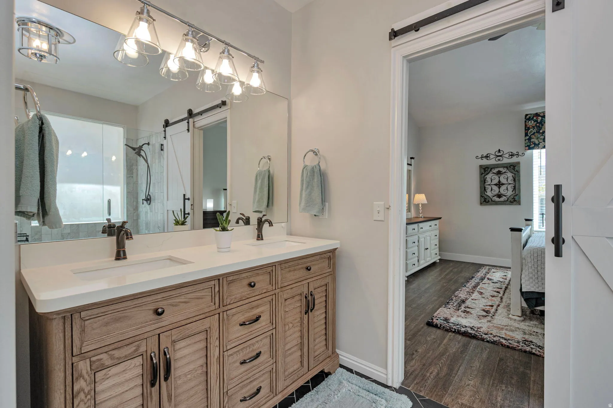 Bathroom vanity featuring dual under-mount sinks, a light-toned countertop, and a wood-finish cabinet with louvered doors