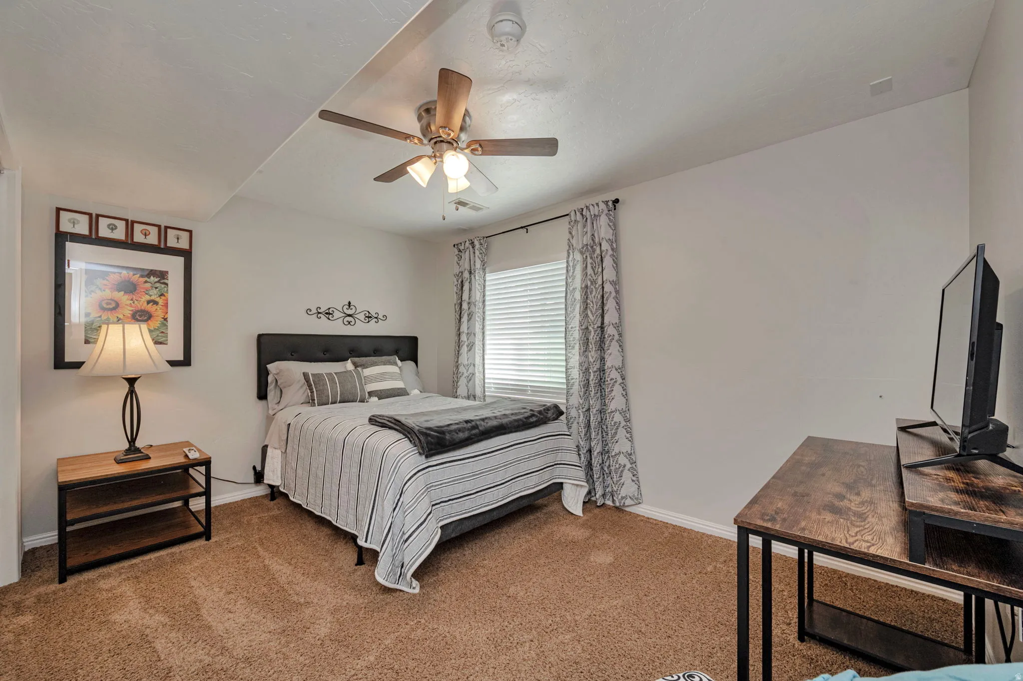 Carpeted room featuring a ceiling fan with integrated lighting, a window with blinds, and white walls