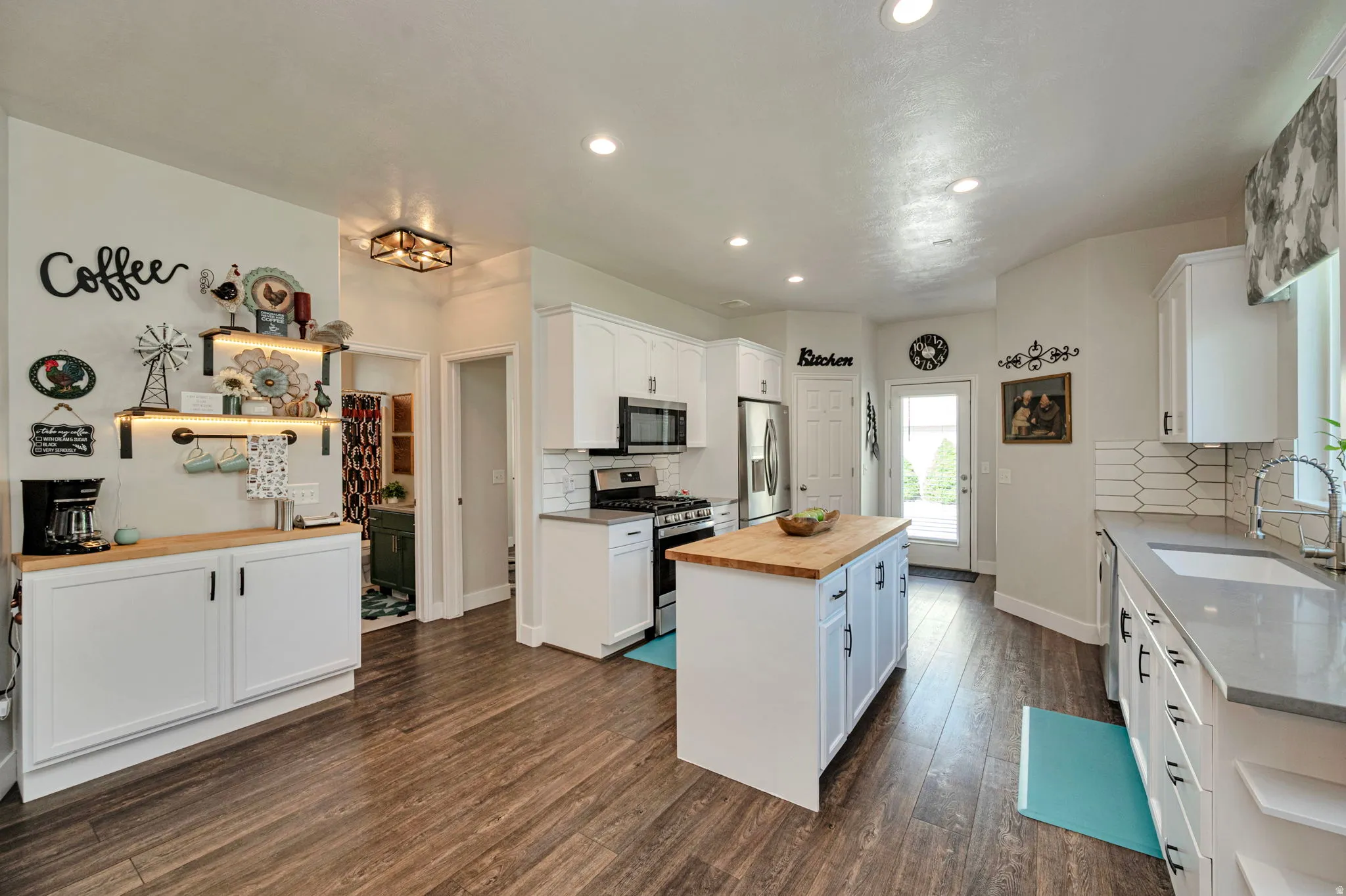 Open-concept kitchen featuring wood-finish flooring, white cabinetry, recessed lighting, and a kitchen island with a butcher block countertop