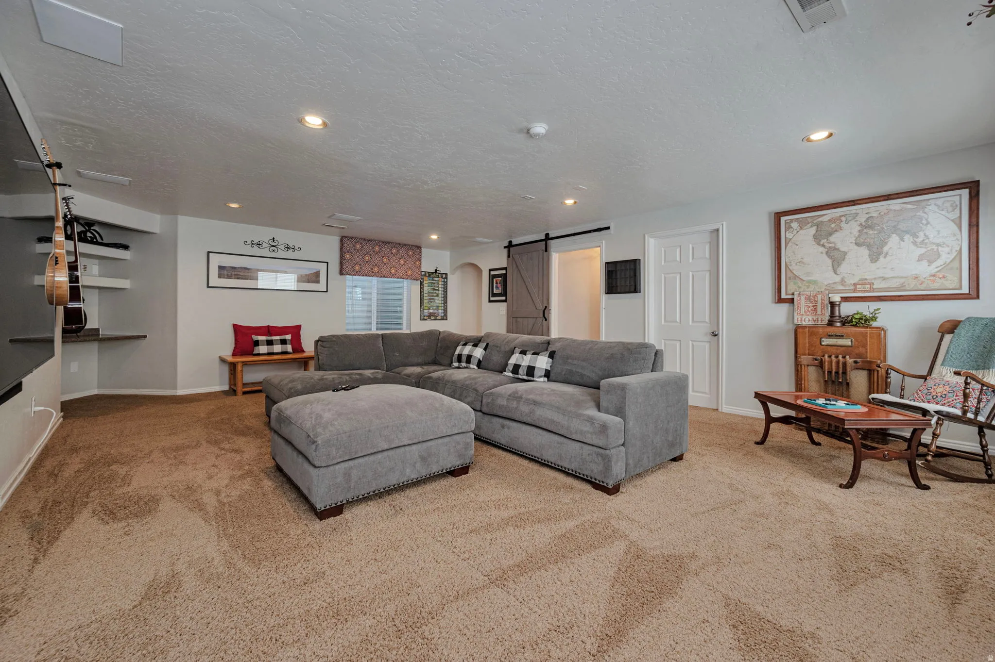 Spacious room featuring neutral carpeting, recessed lighting, white trim, and a barn door entry