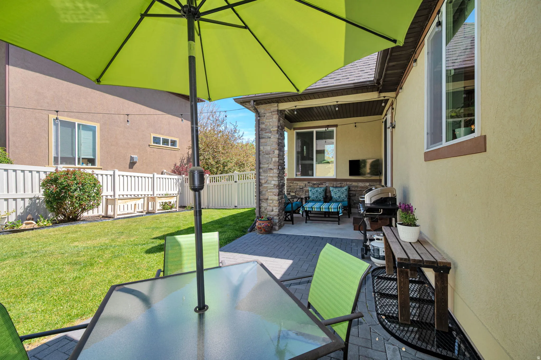 Exterior patio featuring a covered area with recessed lighting, stone-clad columns, and a paved surface