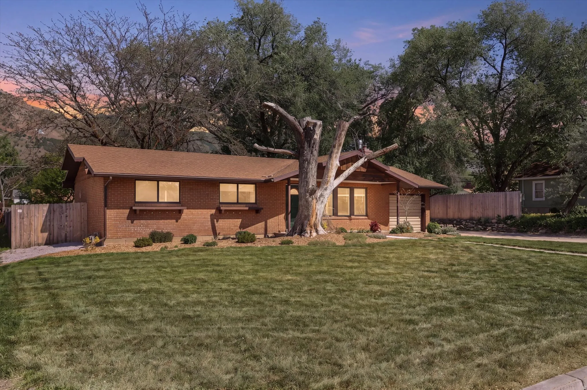 Brick-clad exterior featuring a brown shingle roof and a spacious front lawn