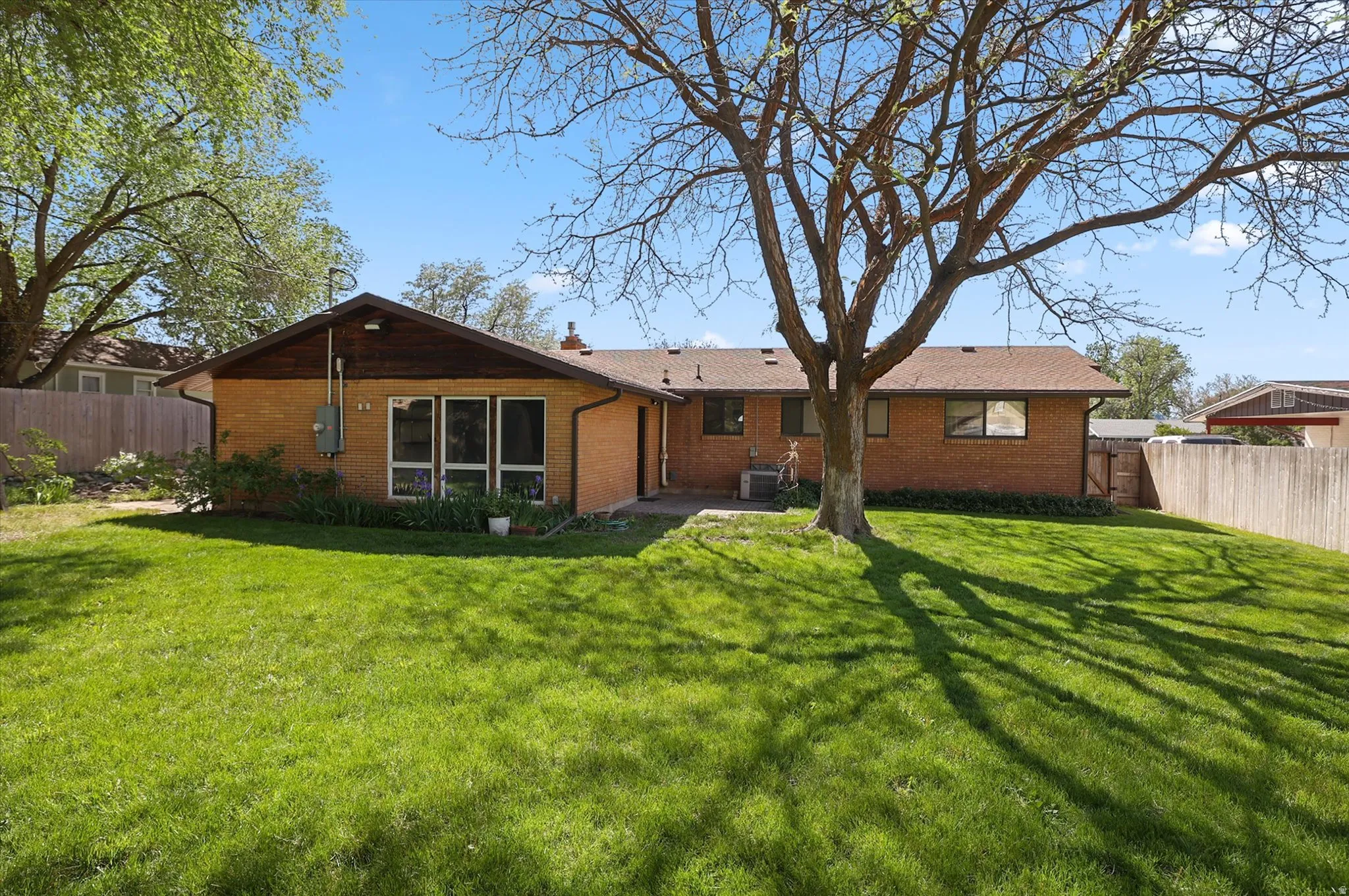 Expansive green lawn with mature trees and a fenced perimeter
