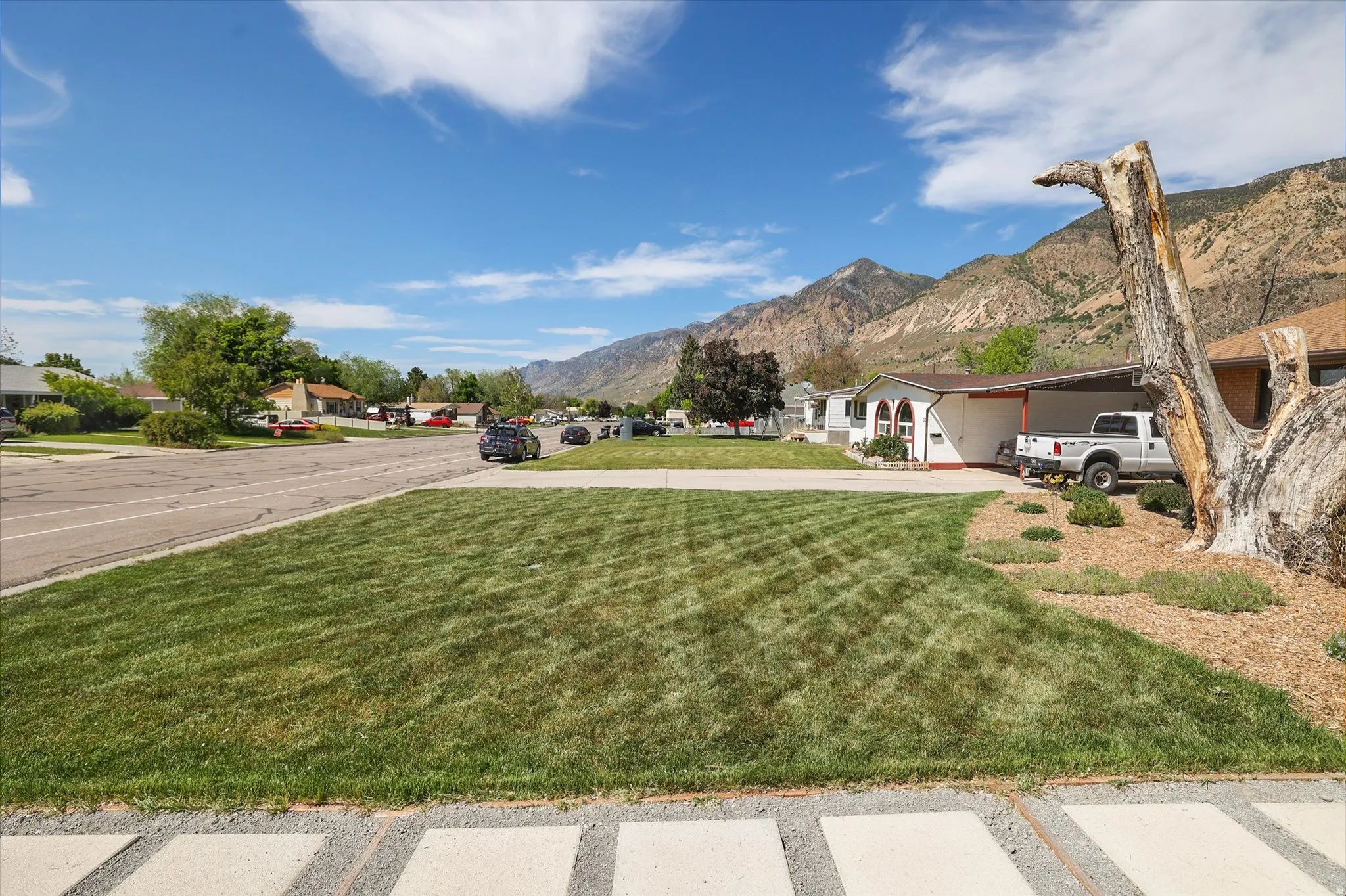 Expansive front lawn with defined mowing patterns, complemented by a drought-tolerant landscape bed featuring wood mulch and low-lying shrubs