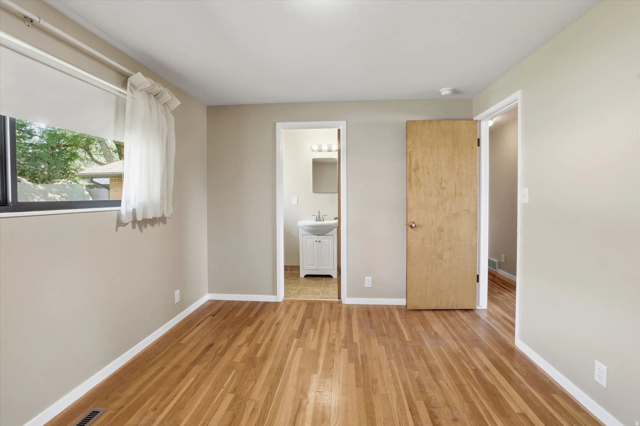 Hardwood flooring throughout, neutral wall paint, and white baseboards