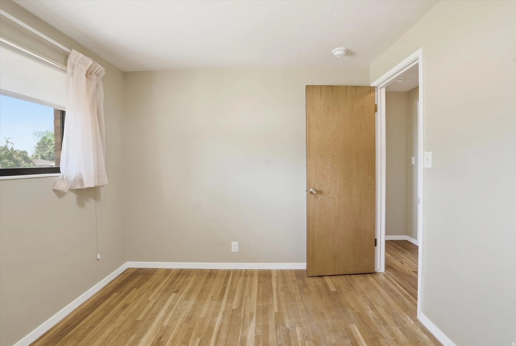 Room featuring wood-finish flooring, a neutral color palette, and a window for natural light