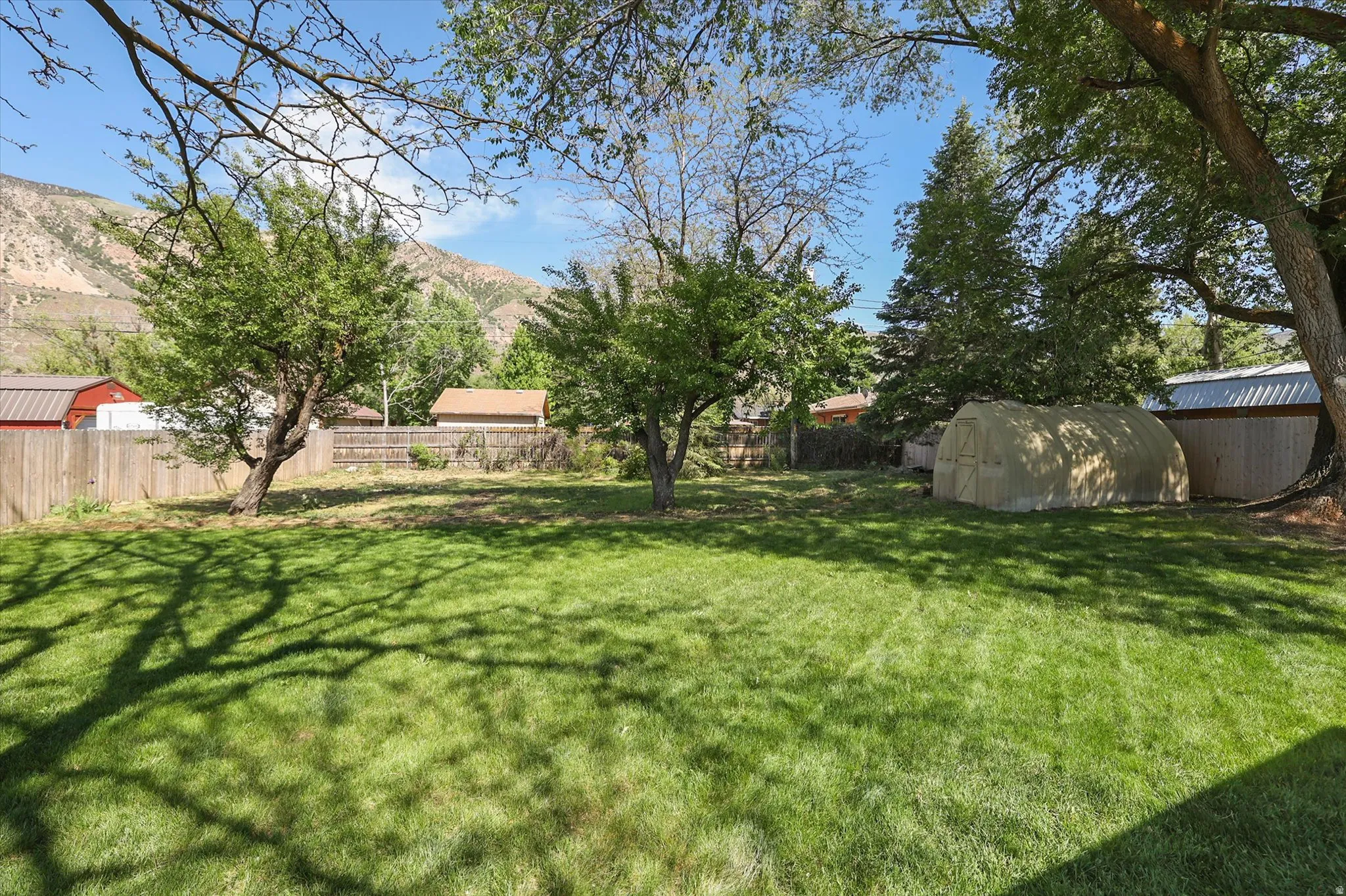 Expansive green lawn with mature trees providing dappled shade
