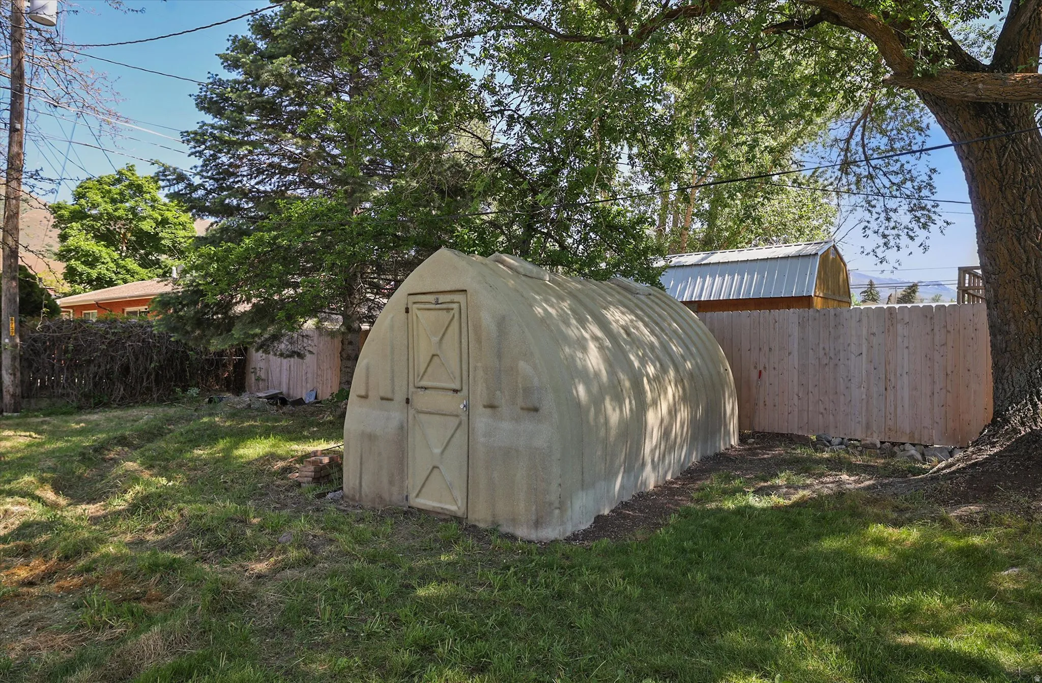 Outdoor storage structure with a light-colored arched roof and a single door