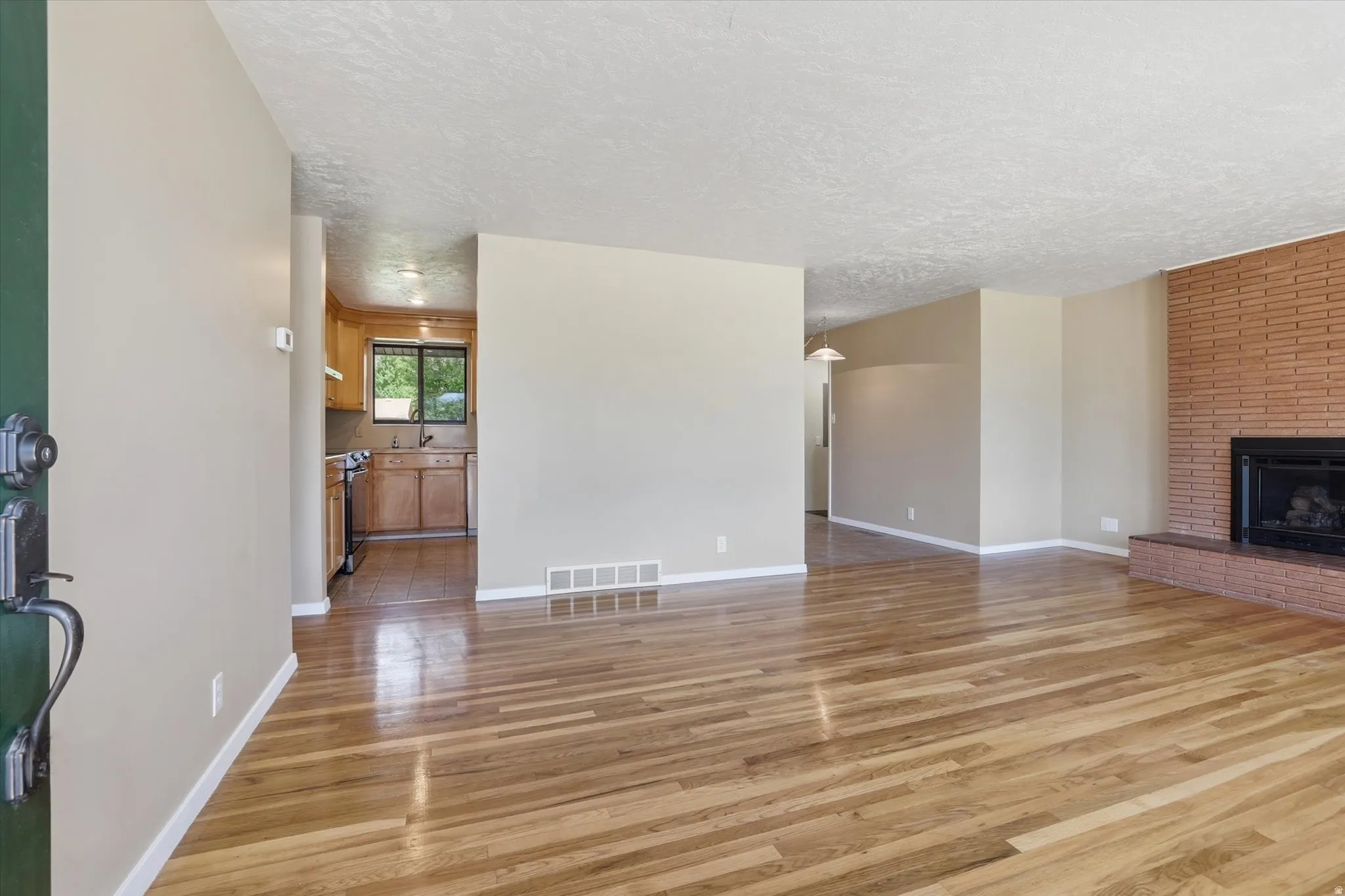Open concept living area featuring wood-finish flooring and a brick-surround fireplace
