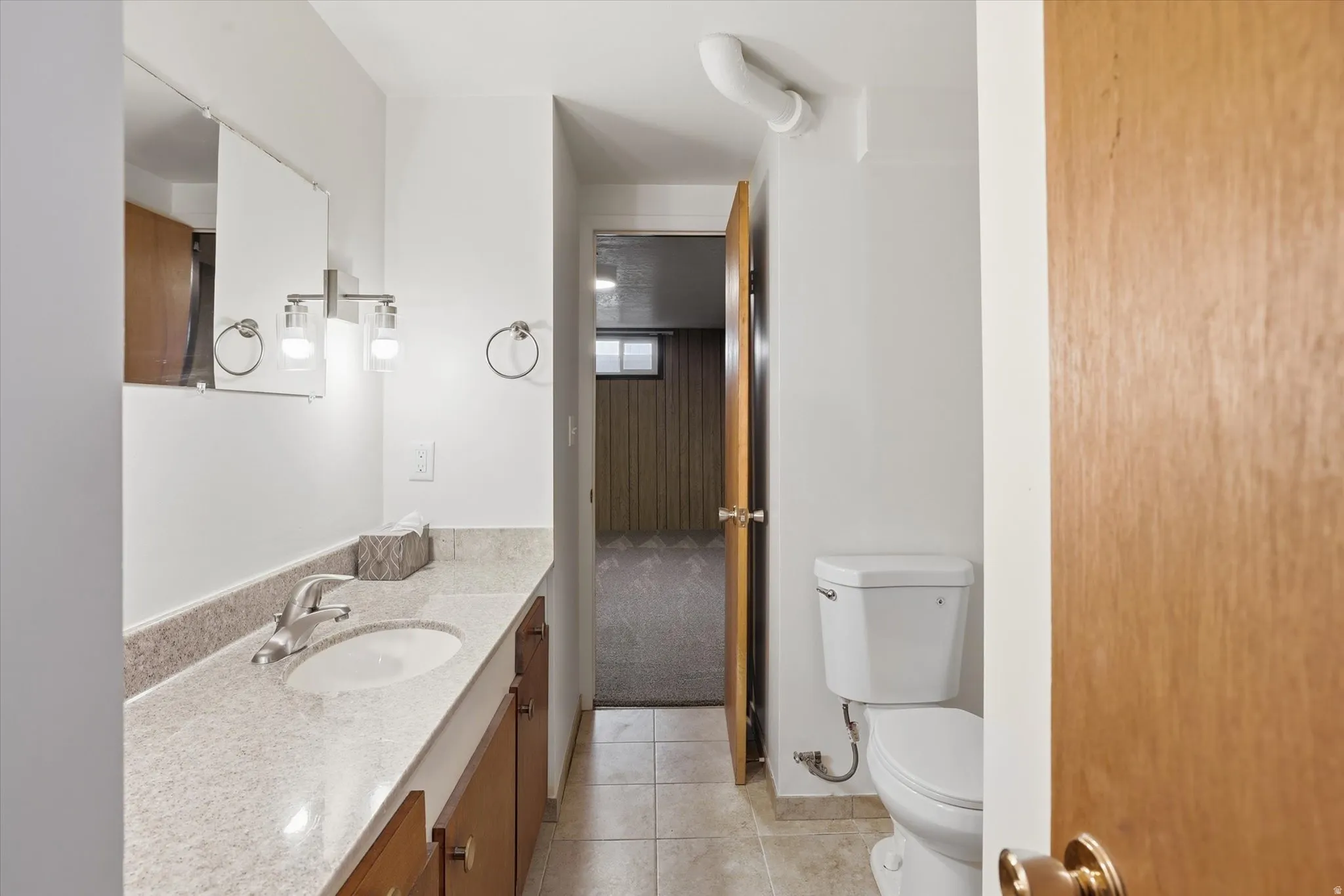 Bathroom featuring a single vanity with a light-toned countertop, an undermount sink, and a brushed nickel faucet