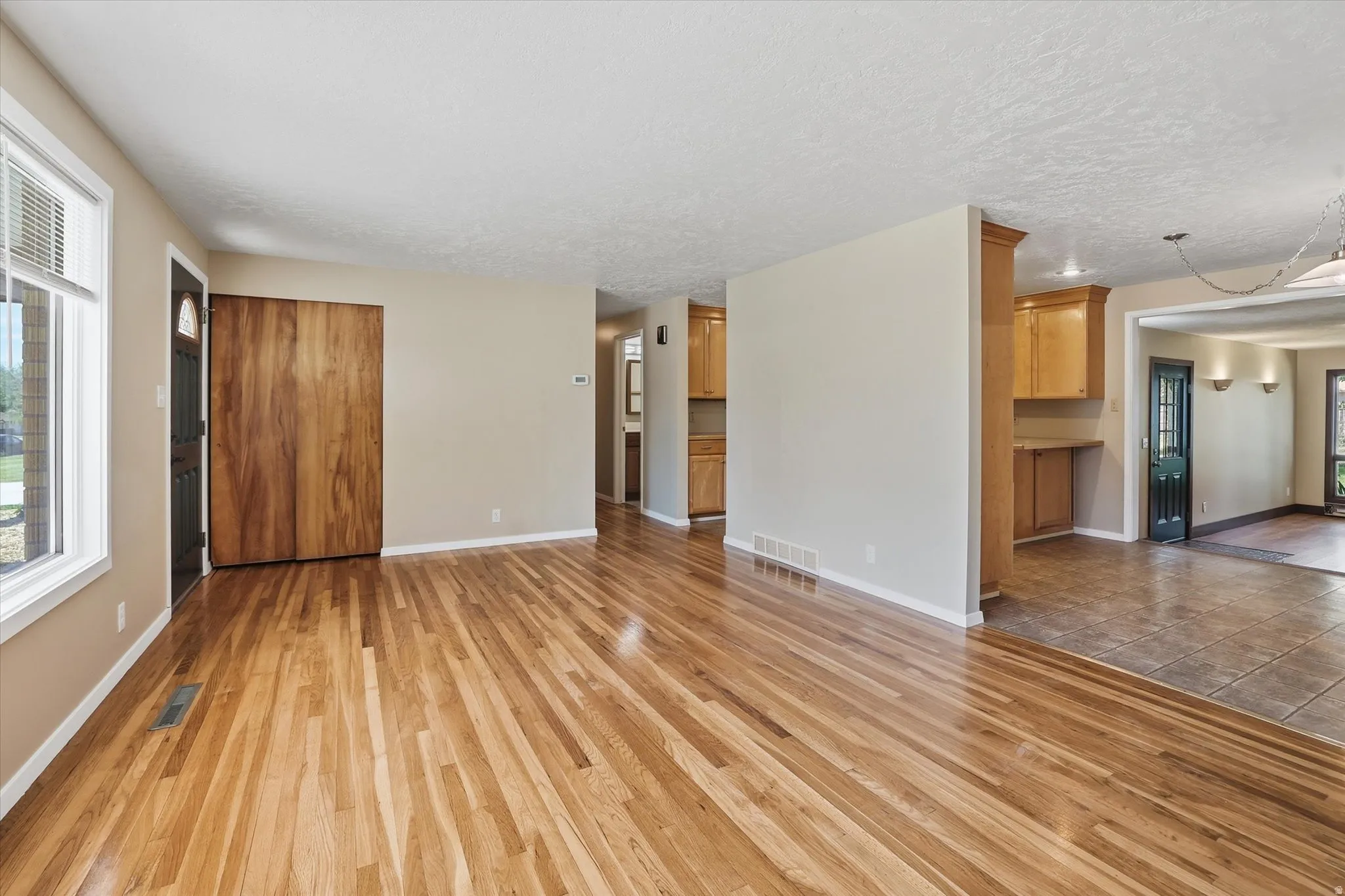 Expansive living area with wood-finish flooring, neutral wall tones, and bright window