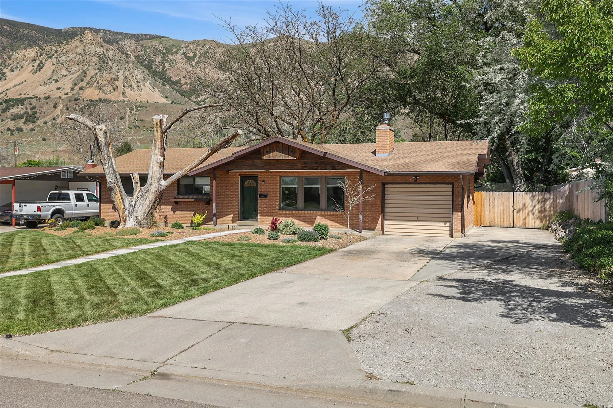 Brick exterior with a brown shingle roof, attached garage, and a separate carport