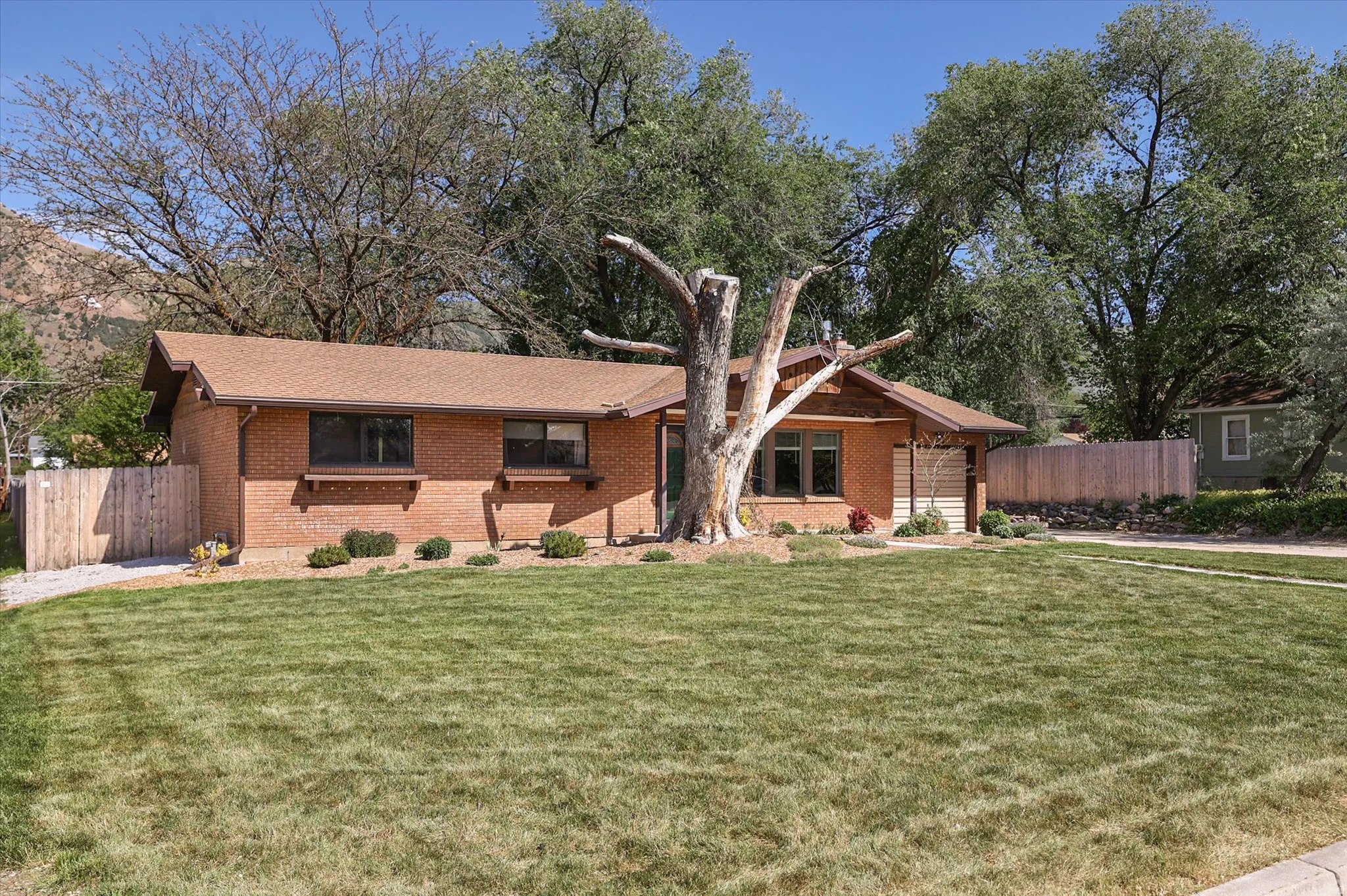 Brick exterior residence featuring a brown shingle roof and a spacious front lawn