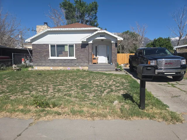 Brick facade residence featuring a front porch, white entry door, and a partially paved driveway