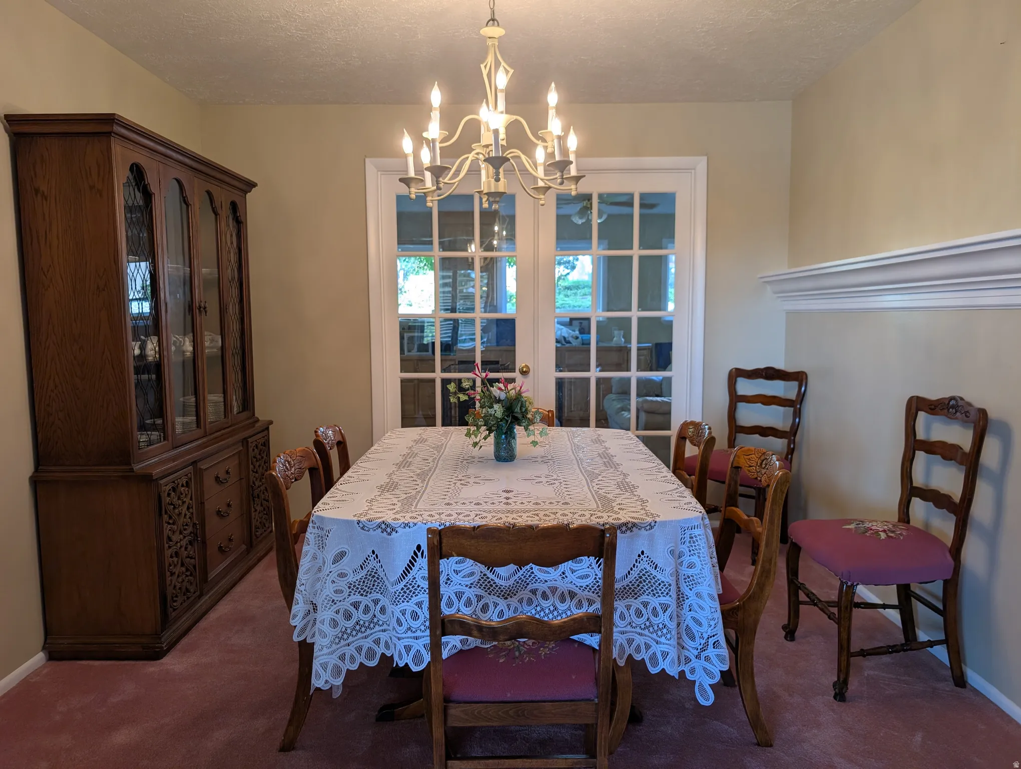 Dining area featuring a central chandelier, light-colored walls, and a decorative chair rail molding