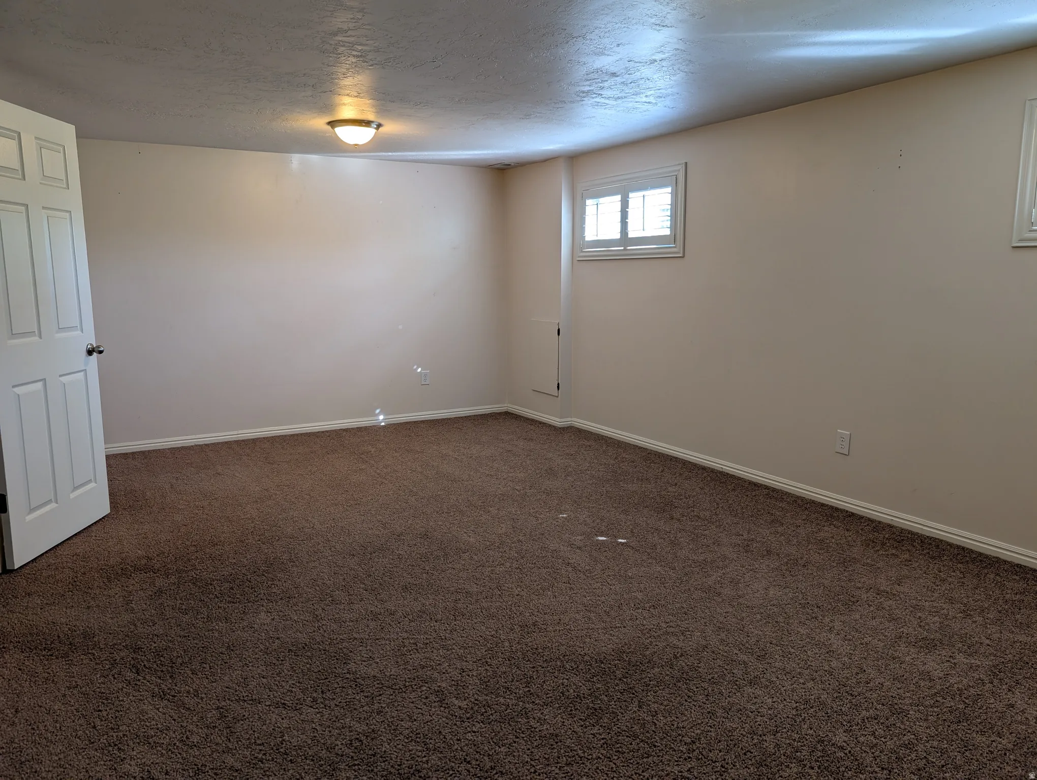 Carpeted room with neutral wall tones and white baseboards