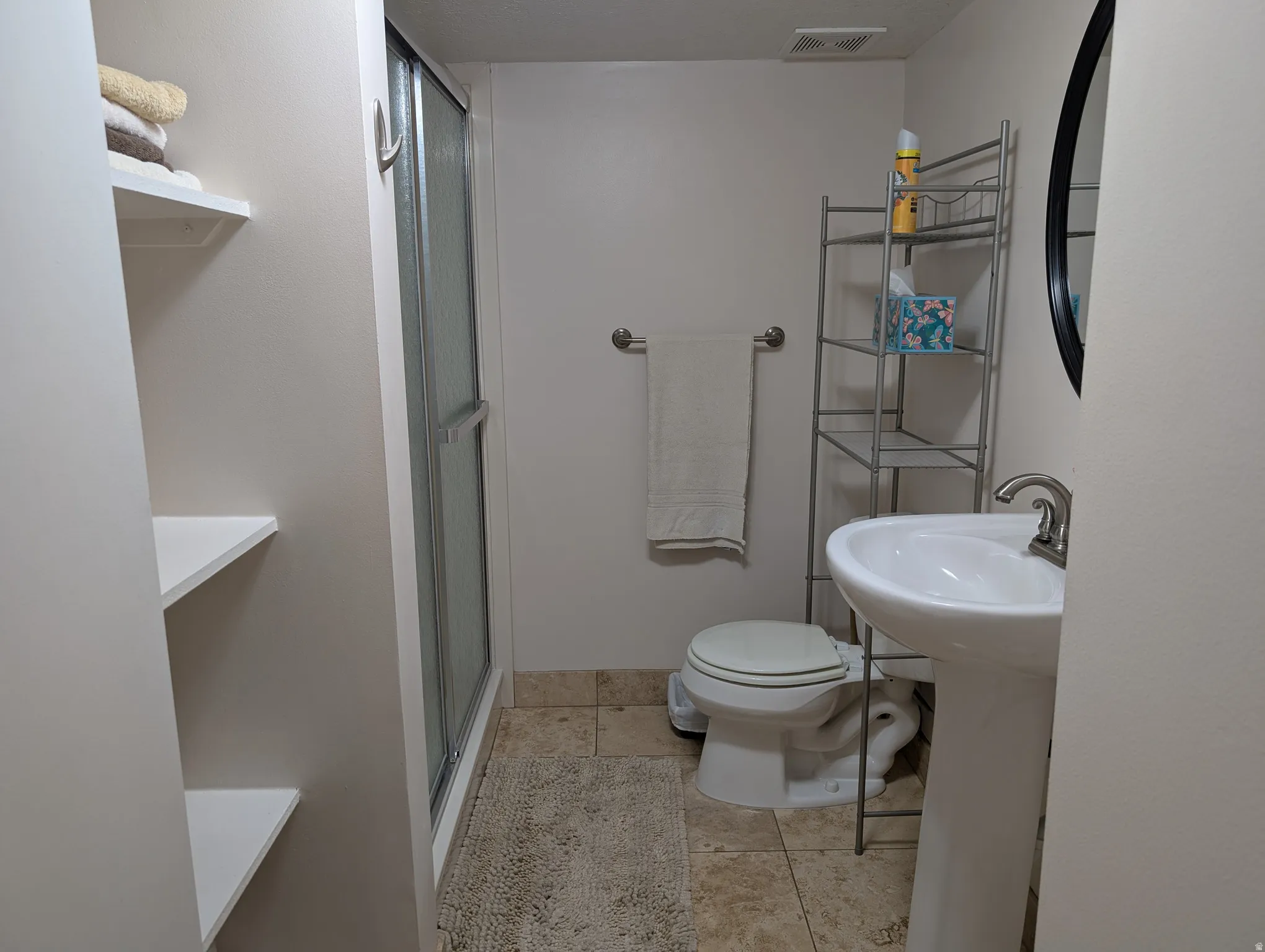 Bathroom featuring a pedestal sink with a brushed nickel faucet, a toilet, and a shower with a sliding glass door
