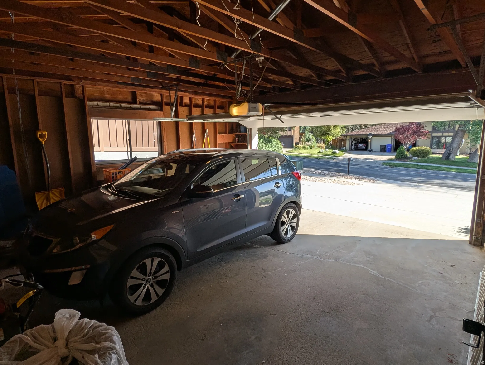 Attached garage featuring exposed wood framing and a concrete floor