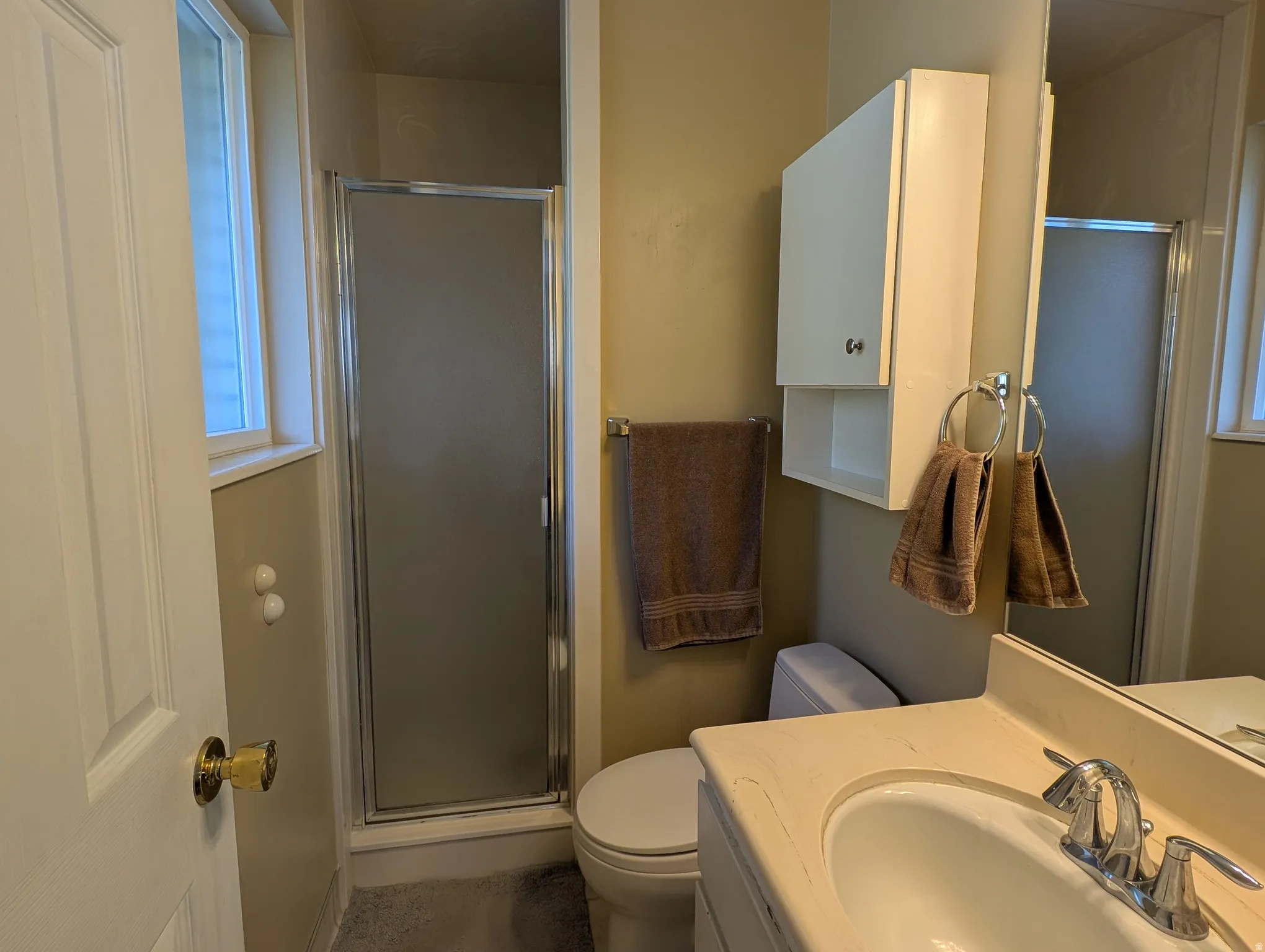 Master bathroom featuring a shower with a framed frosted glass enclosure, a window providing natural light, and a vanity with an integrated sink
