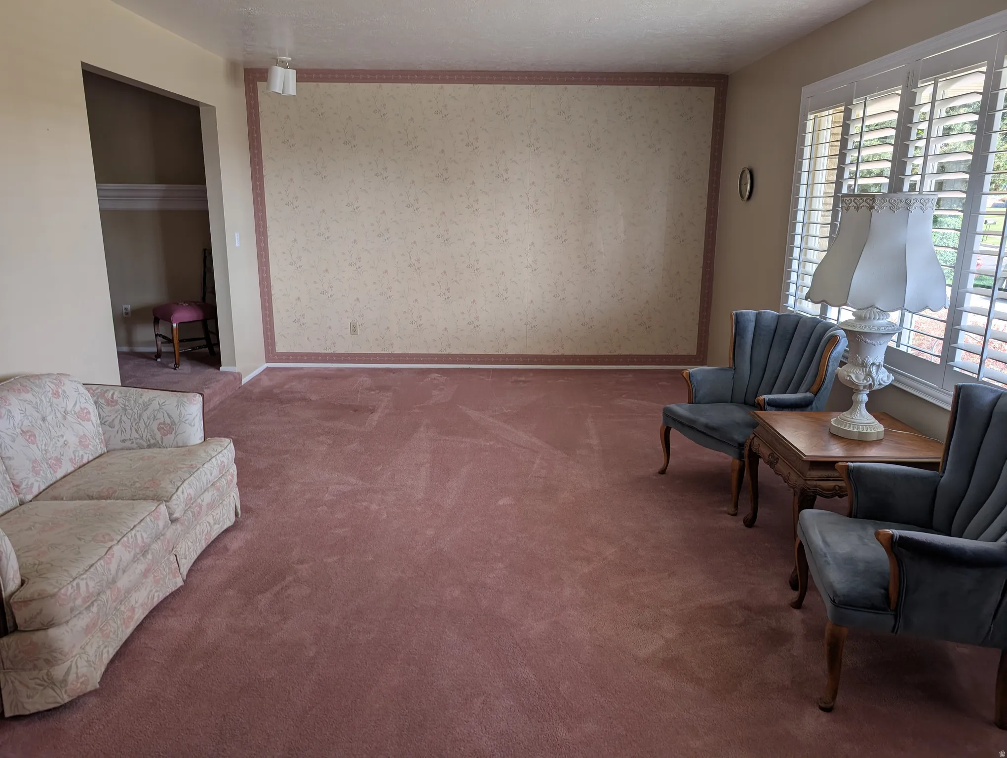 Spacious living room featuring plush carpeting and a textured accent wall