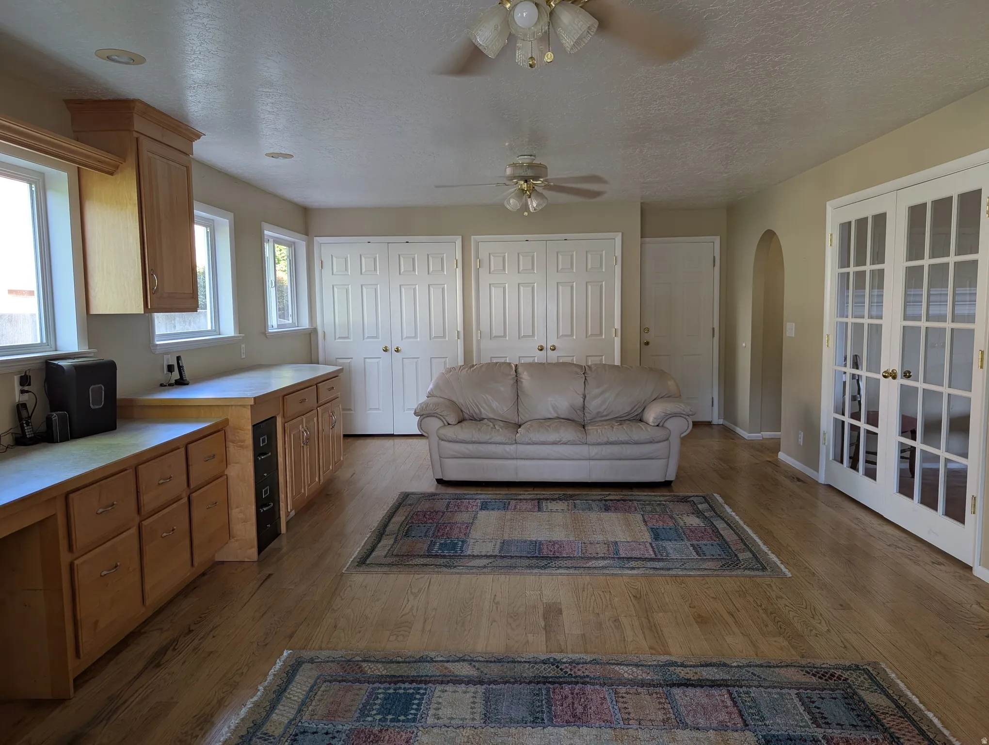 Spacious family room featuring wood-finish flooring, light wood cabinetry with integrated desk space, and multiple windows