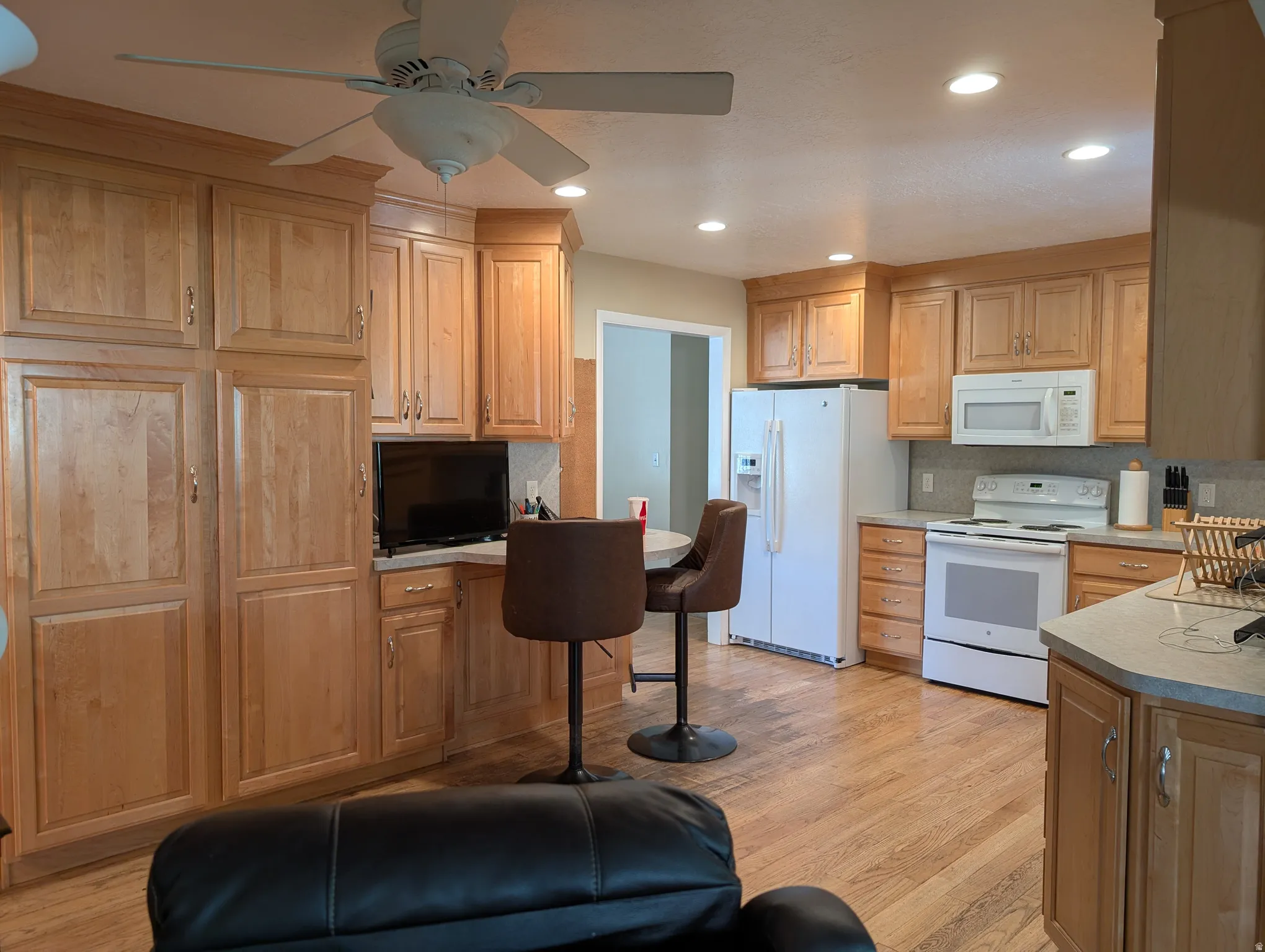 Kitchen featuring wood-finish flooring, recessed lighting, a ceiling fan, light wood cabinetry providing ample storage, and white appliances