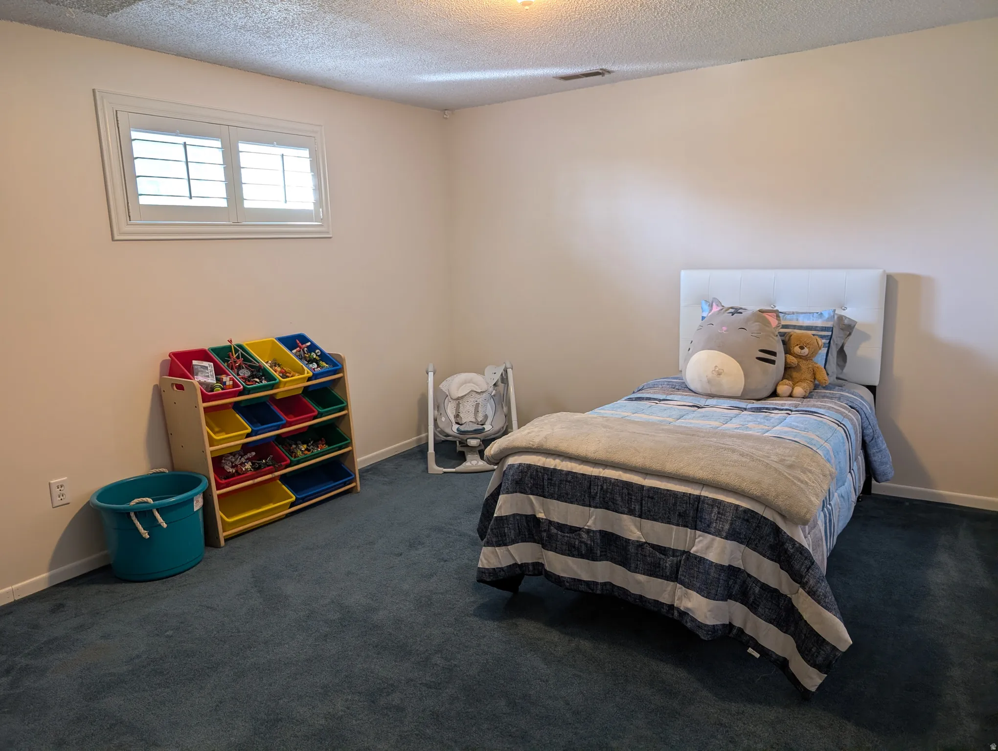 Neutral wall paint with baseboard trim and dark blue carpeting
