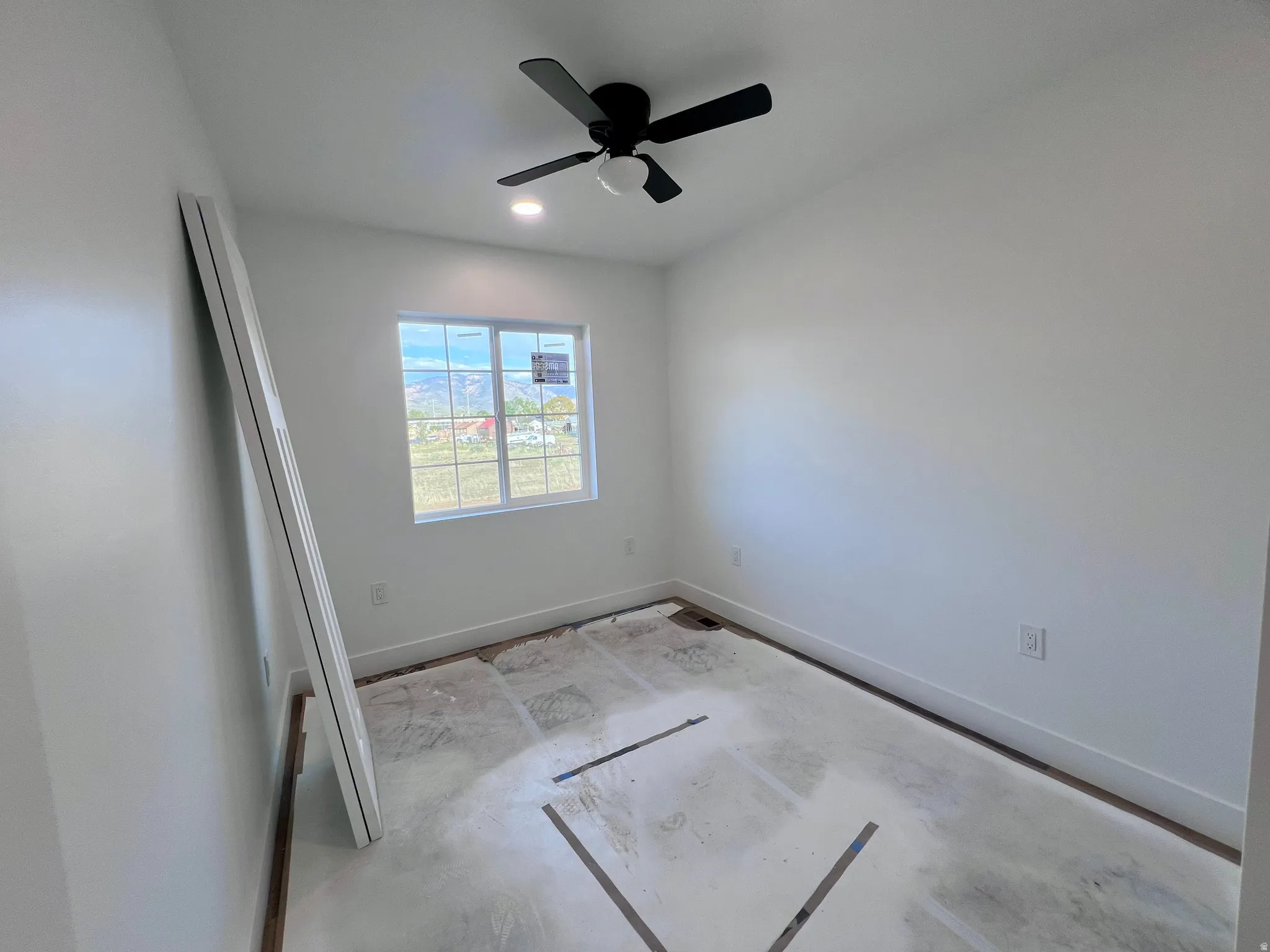 Bright interior space featuring a double-pane window, white walls, and a black ceiling fan with an integrated light fixture