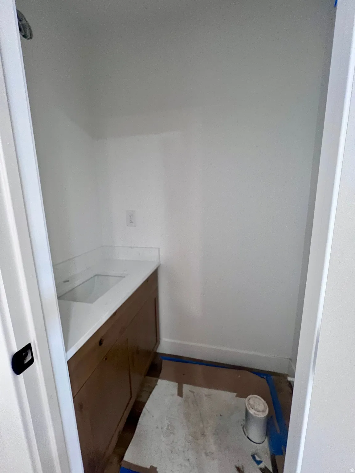 Built-in vanity with wood-finish cabinetry, integrated sink, and light-toned countertop